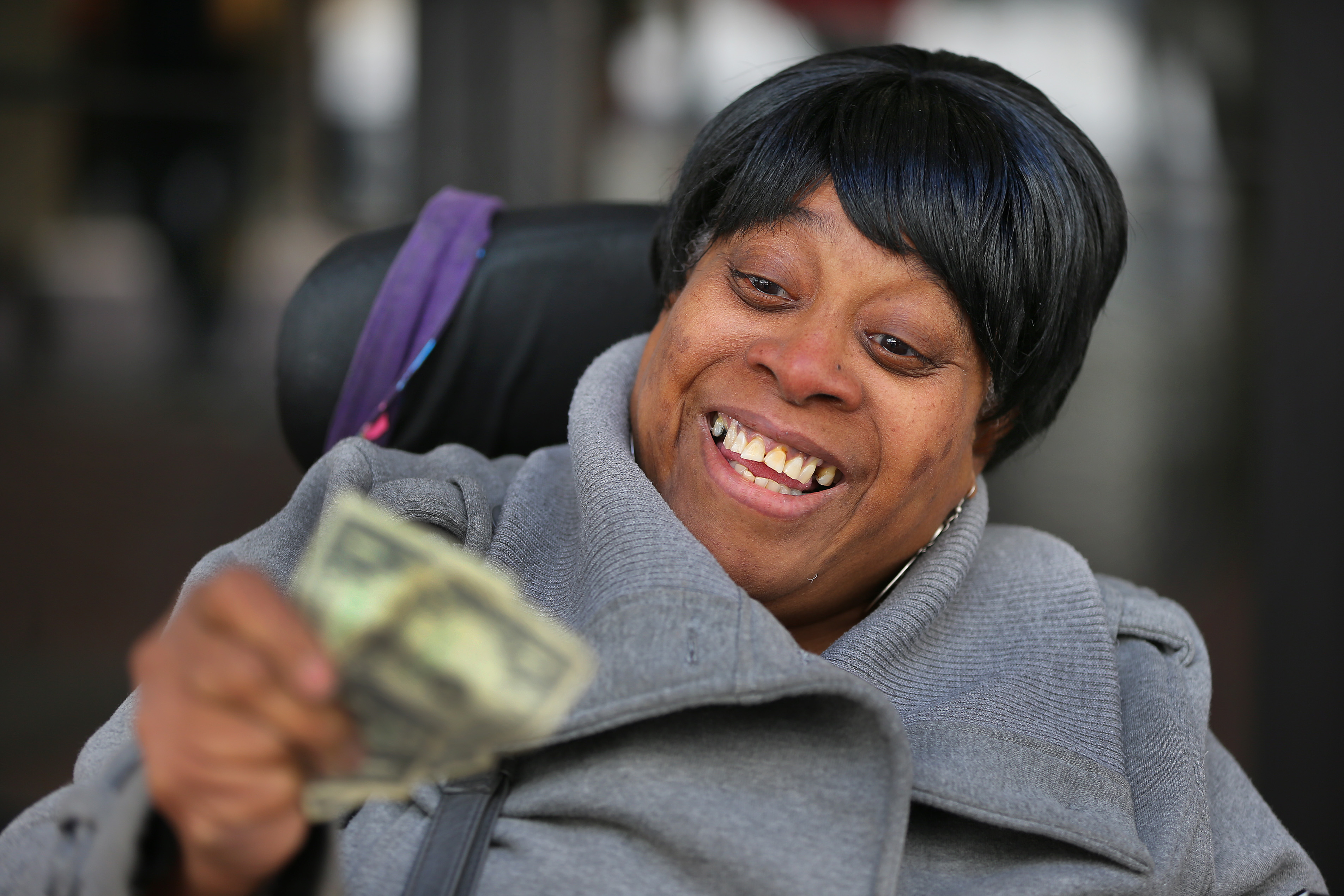 Rhonda Gibson, from Malden, examined the bills she received at Downtown Crossing. Gibson, who is in a wheel chair, said "Now I have my bus money to get home."