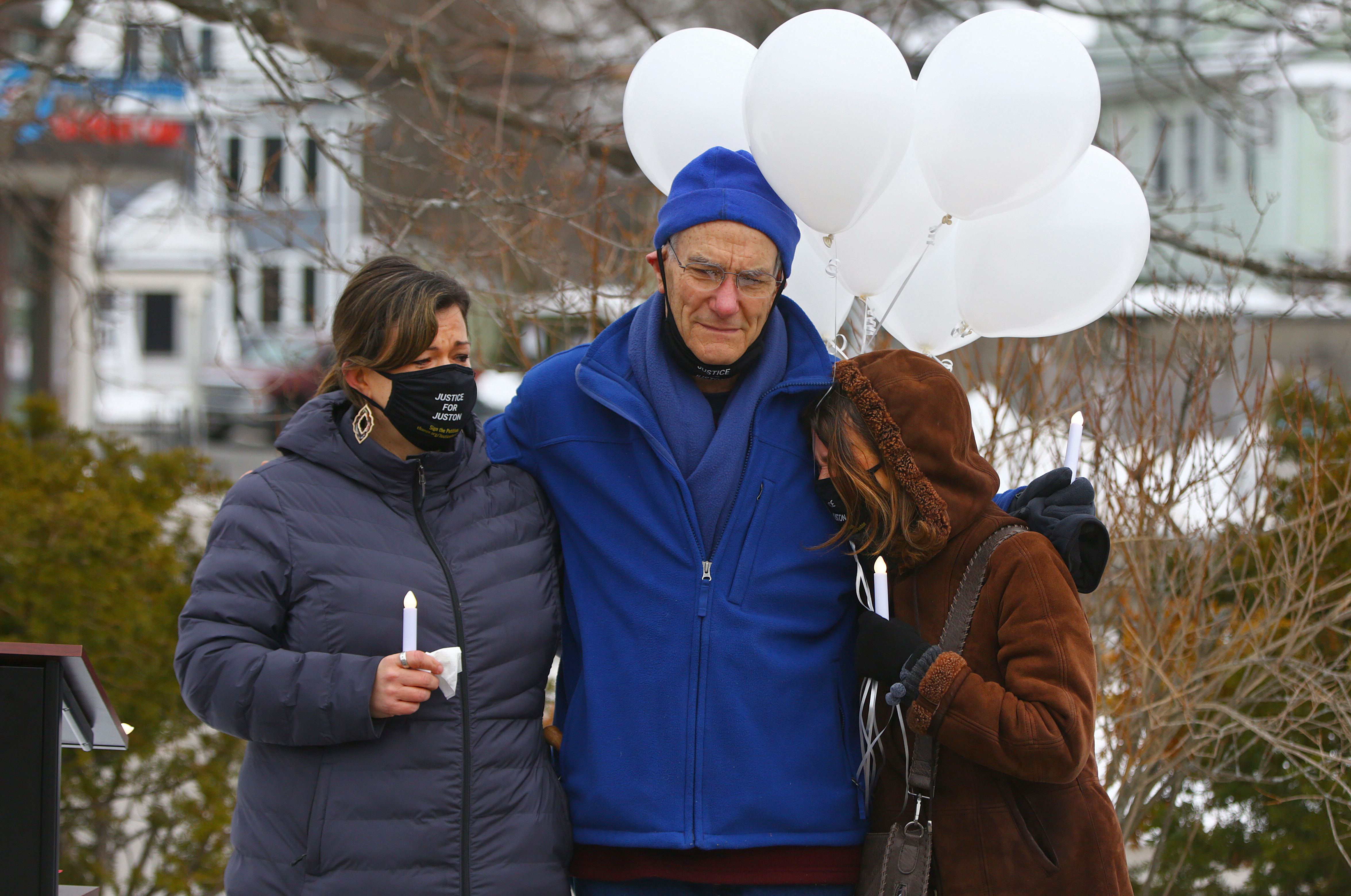 From left, Juston Root's sister, father, and stepmother — Jennifer Root Bannon, Evan Root, and Maureen Root — embraced in silence Sunday before releasing balloons in his memory.