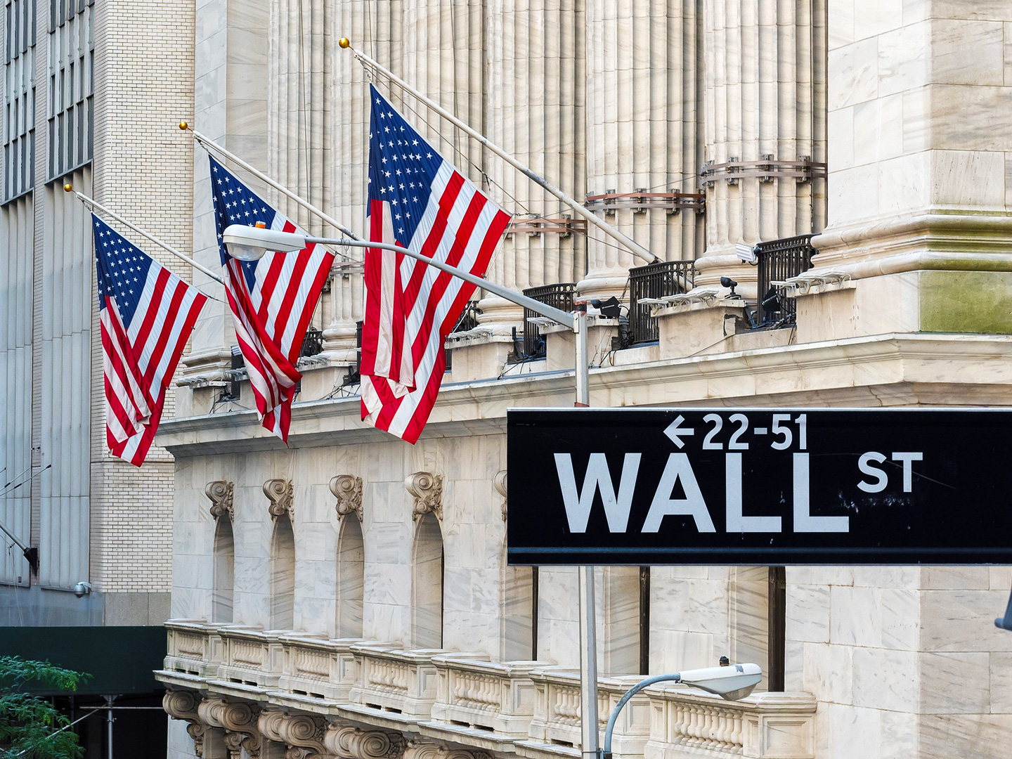 Wall Street sign with American flags and New York Stock Exchange in Manhattan, New York City, USA. (Getty Images)