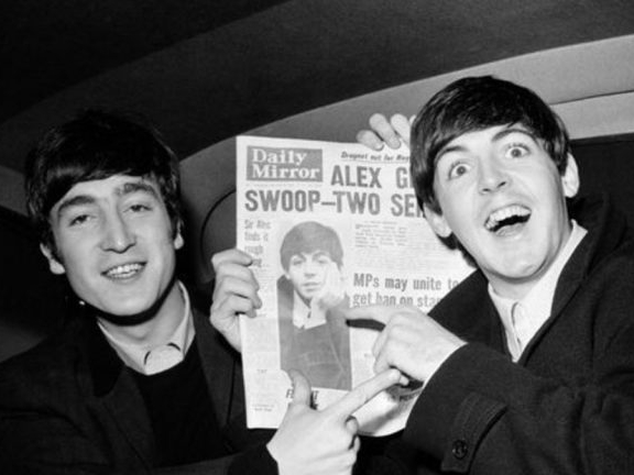 John Lennon y Paul McCartney sosteniendo un diario.