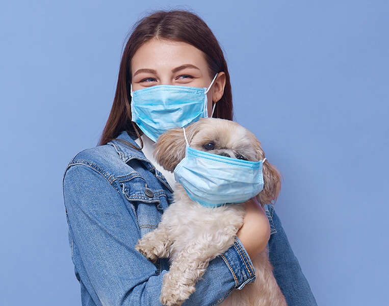 Young girl wearing medical mask with her pet, standing against b