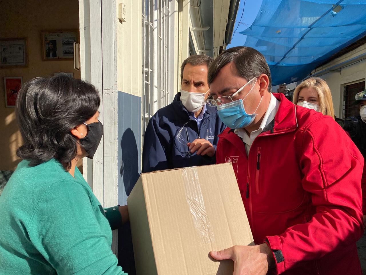 Felipe Guevara y Felipe Alessandri entregan una caja de mercadería del Gobierno.