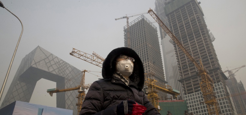 A woman wears a mask as she walks past a construction site as smog co