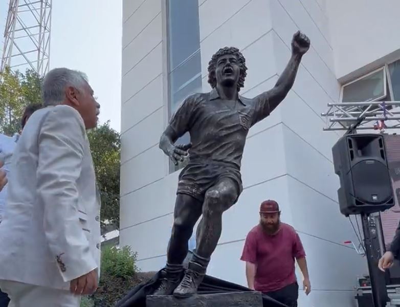 Carlos Caszely observa la estatua que lo homenajea.