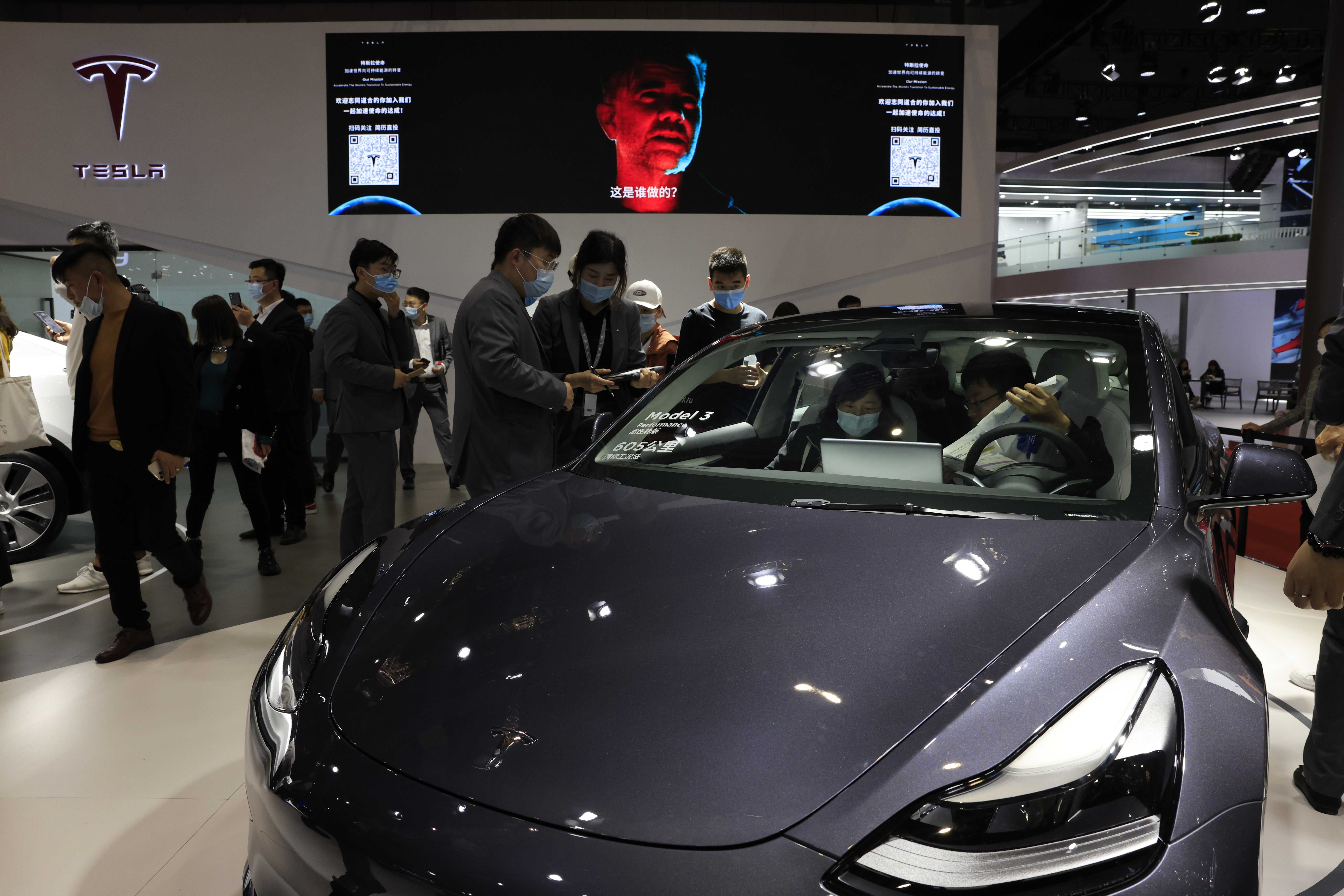 Visitors look at a Tesla Model 3 during the Shanghai Auto Show in Shanghai on Wednesday, April 21, 2021. (AP Photo/Ng Han Guan)