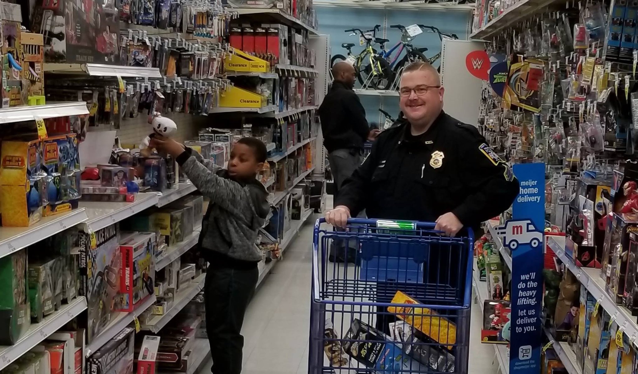 Sgt. Cris Kelly helps a young child shop during the Middletown Division of Police Mike Davis Christmas With A Cop program this month at Meijer.