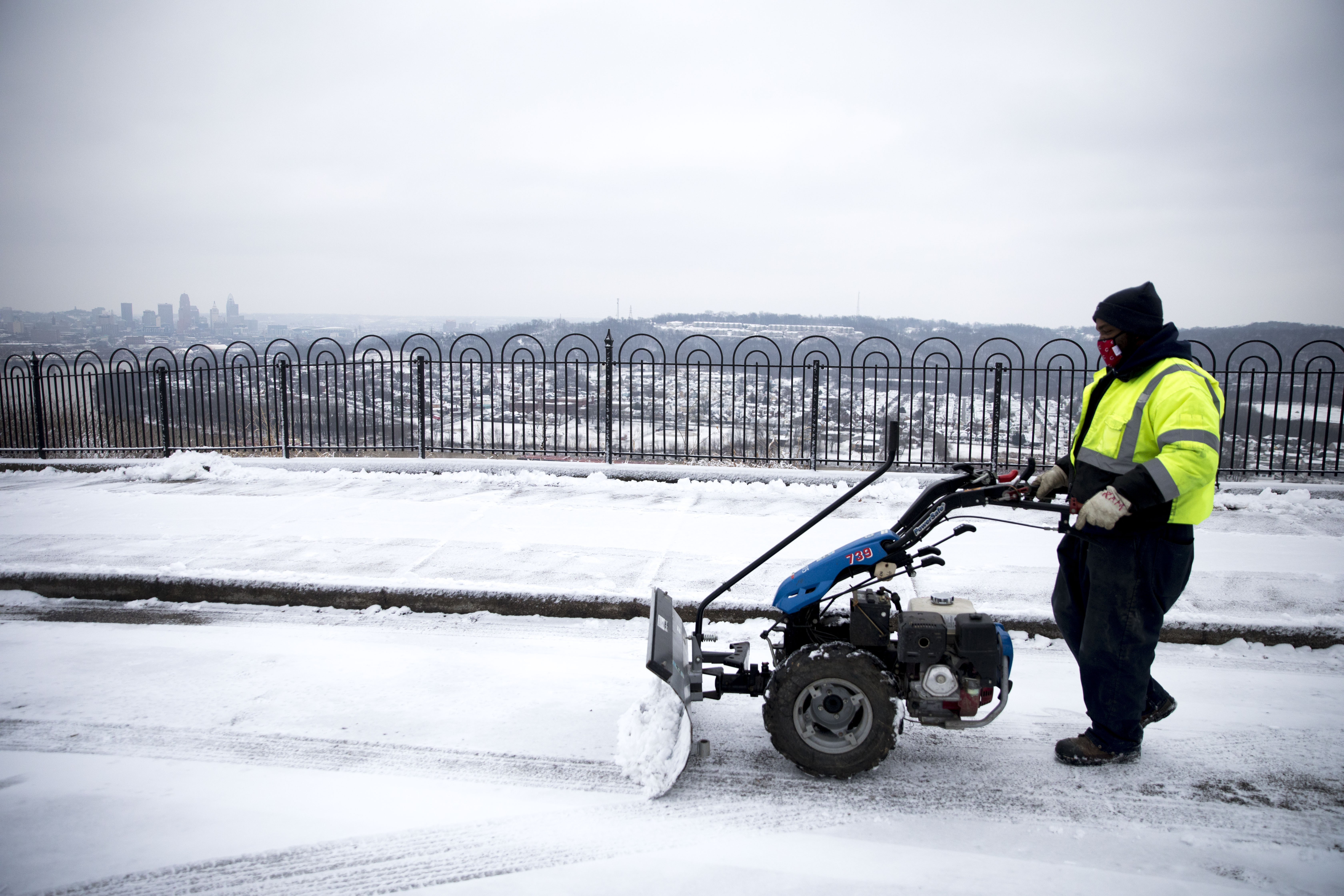 Cincinnati City Parks worker Kevin Manuel clears snow off the parking area at Mt. Echo Park in Cincinnati, Ohio, on Monday, Feb. 1, 2021. (Albert Cesare/The Cincinnati Enquirer via AP)