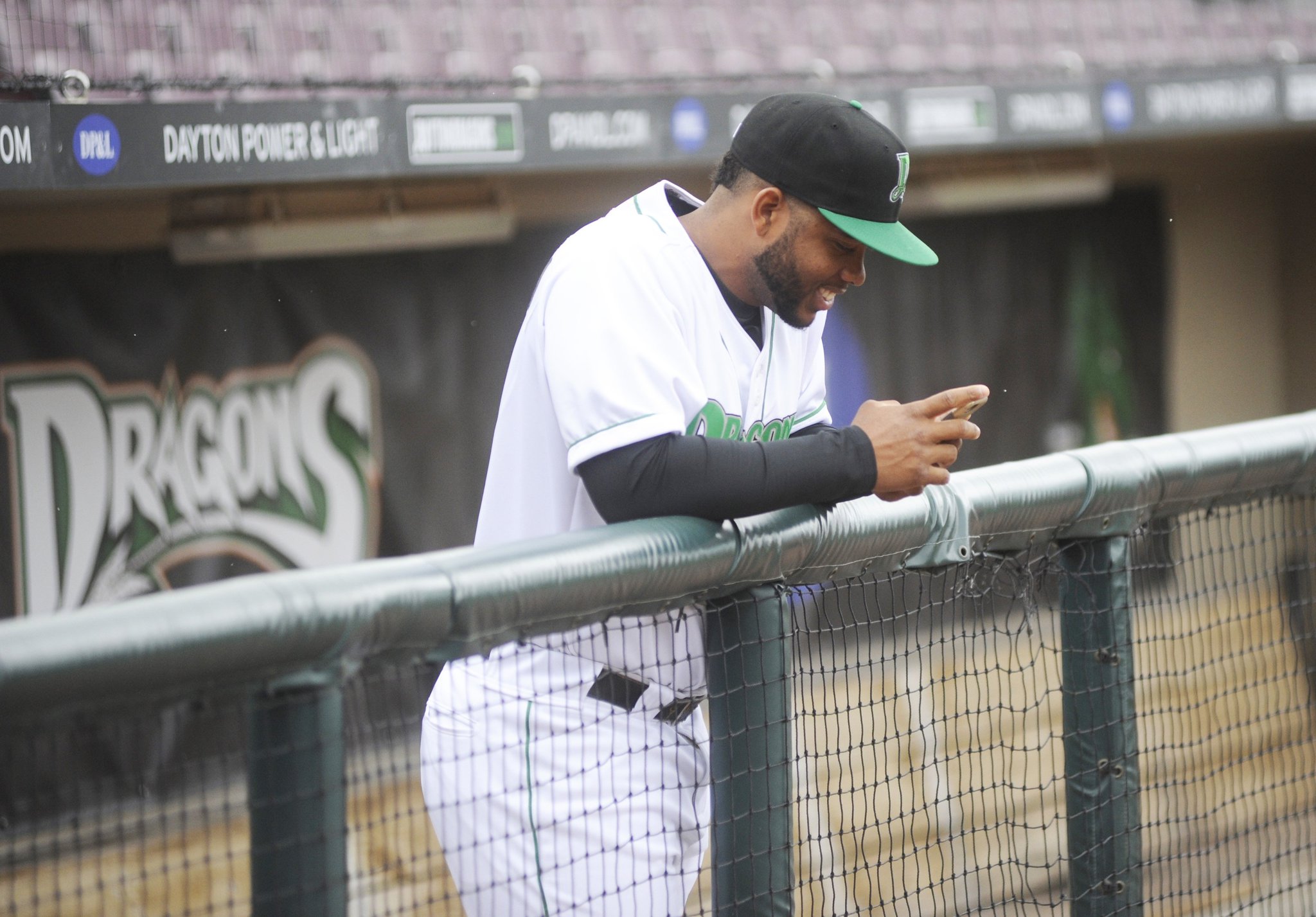 Dragons catcher Hendrik Clementina checks a text message in the Dragons’ dugout prior to a final preseason workout at Dayton’s Fifth Third Field on Wednesday, April 4, 2018. MARC PENDLETON / STAFF