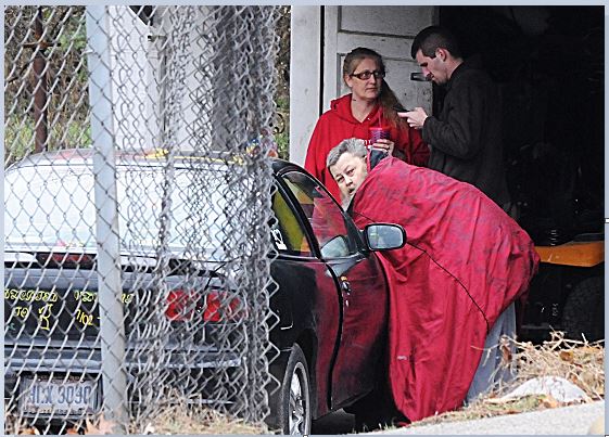 The man leaning on the car was rescued from a house fire Wednesday afternoon when a Dayton woman said she saw him waving and heard him asking for help. (Marshall Gorby/Staff)