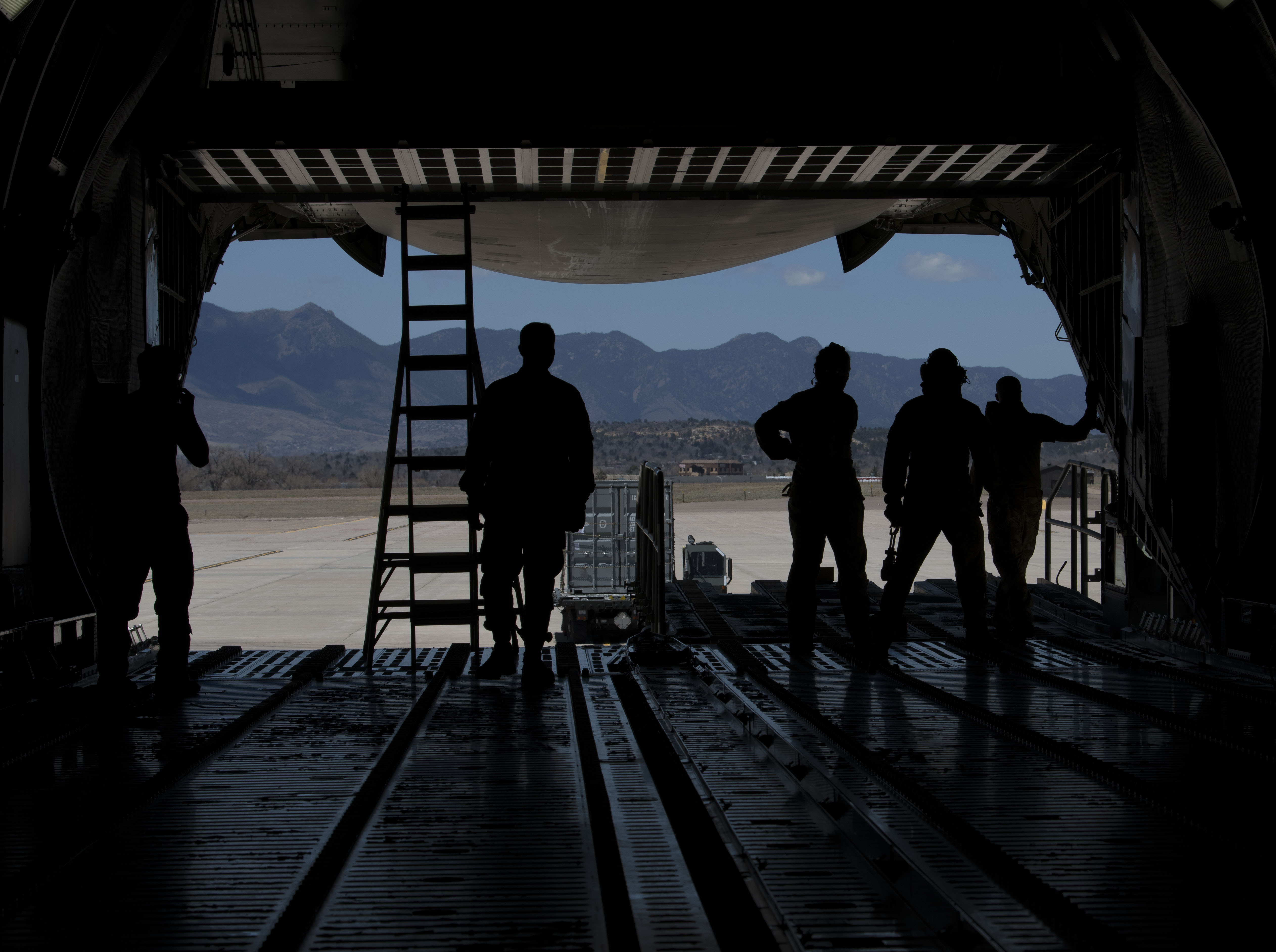 Airmen from the 21st Logistics Readiness Squadron, the 22nd Airlift Squadron watch as a K Loader is directed after putting cargo pallets onto a C-5M Super Galaxy in April on Peterson Air Force Base, Colo. Peterson AFB photo