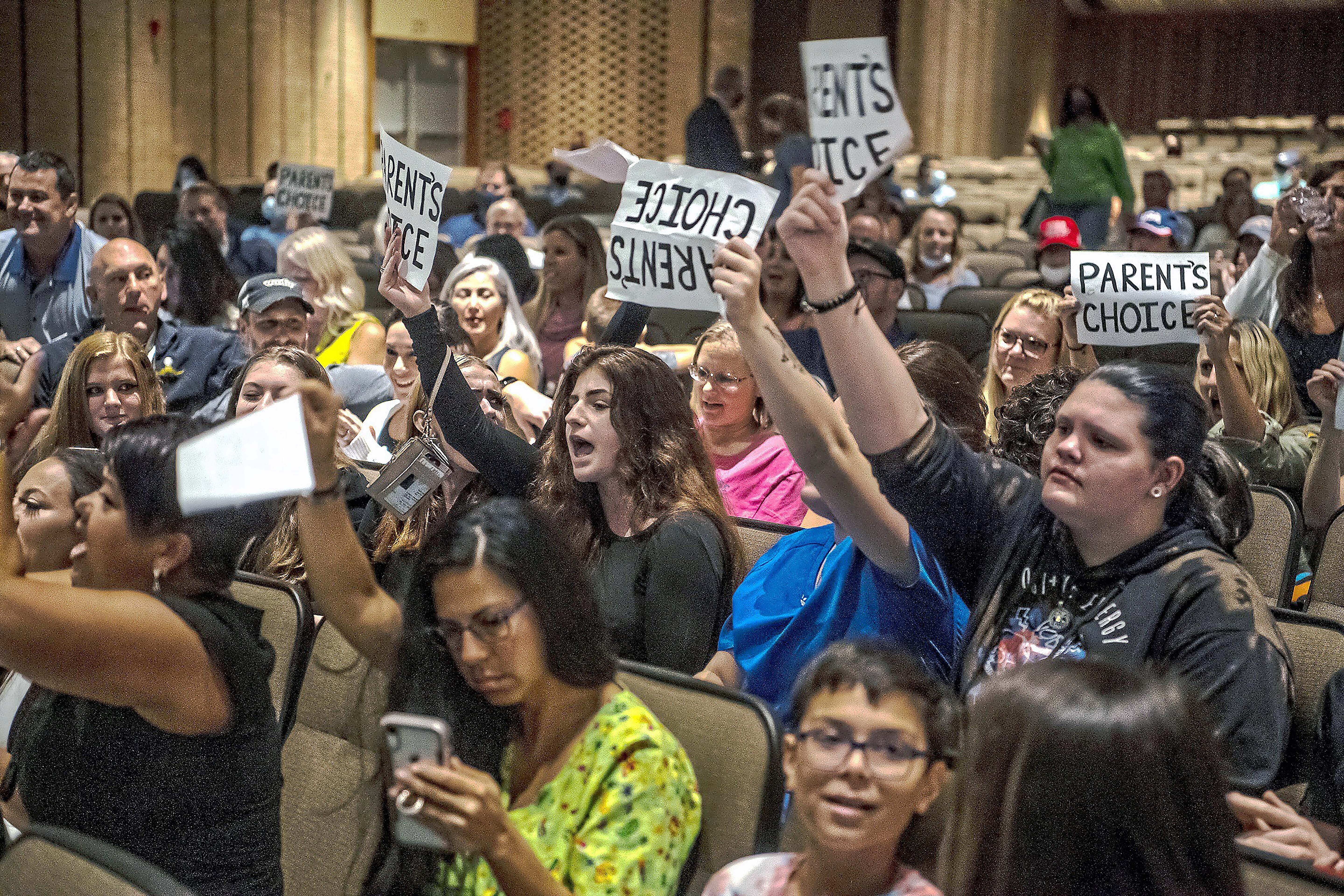 FILE - People hold signs and chant during a meeting of the North Allegheny School District school board regarding the district's mask policy, at at North Allegheny Senior High School in McCandless, Pa., Aug. 25, 2021. School board candidates opposing mask mandates and lessons about racism in U.S. history won in red states and some politically divided districts but often came up short in their bids to shape policy for school districts over the newest culture war issue. (Alexandra Wimley/Pittsburgh Post-Gazette via AP, File)