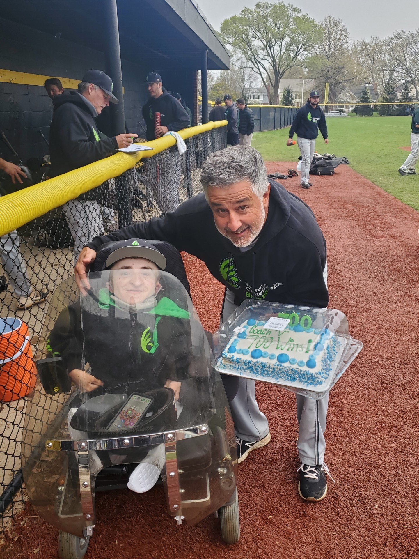 Wilmington coach Tony Vittorio celebrates his 700th win as college baseball coach with Fightin Quakers assistant coach Daniel “Danny” McCarty, who moves around the field in a motorized wheelchair that he has equipped with a Harley Davidson motorcycle shield to protect his brittle bones from hits or errantly thrown baseballs at games. McCarty said he has suffered over 300 broken bones in his 18 years of life (Contributed Photo)