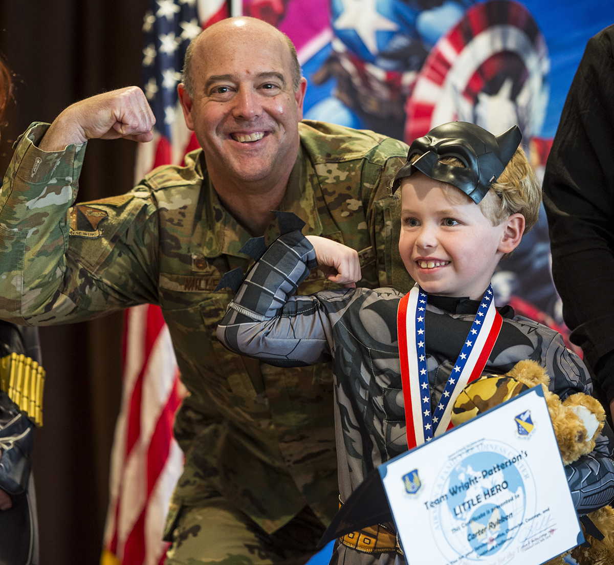 Col. Patrick Miller, 88th Air Base Wing and installation commander, flexes his muscles with a boy dressed as Batman during the “Little Heroes” celebration April 8 at Wright-Patterson Air Force Base. U.S. AIR FORCE PHOTO/JAIMA FOGG