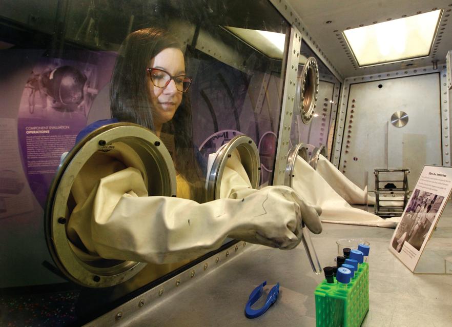 Mandy Askins, the site manager for the Mound Cold War Discovery Center in Miamisburg, demonstrates how Mound Laboratory employees used a glove bos to work with radioactive and dangerous materials. This is one of the interactive activities on site at the new musuem. LISA POWELL / STAFF