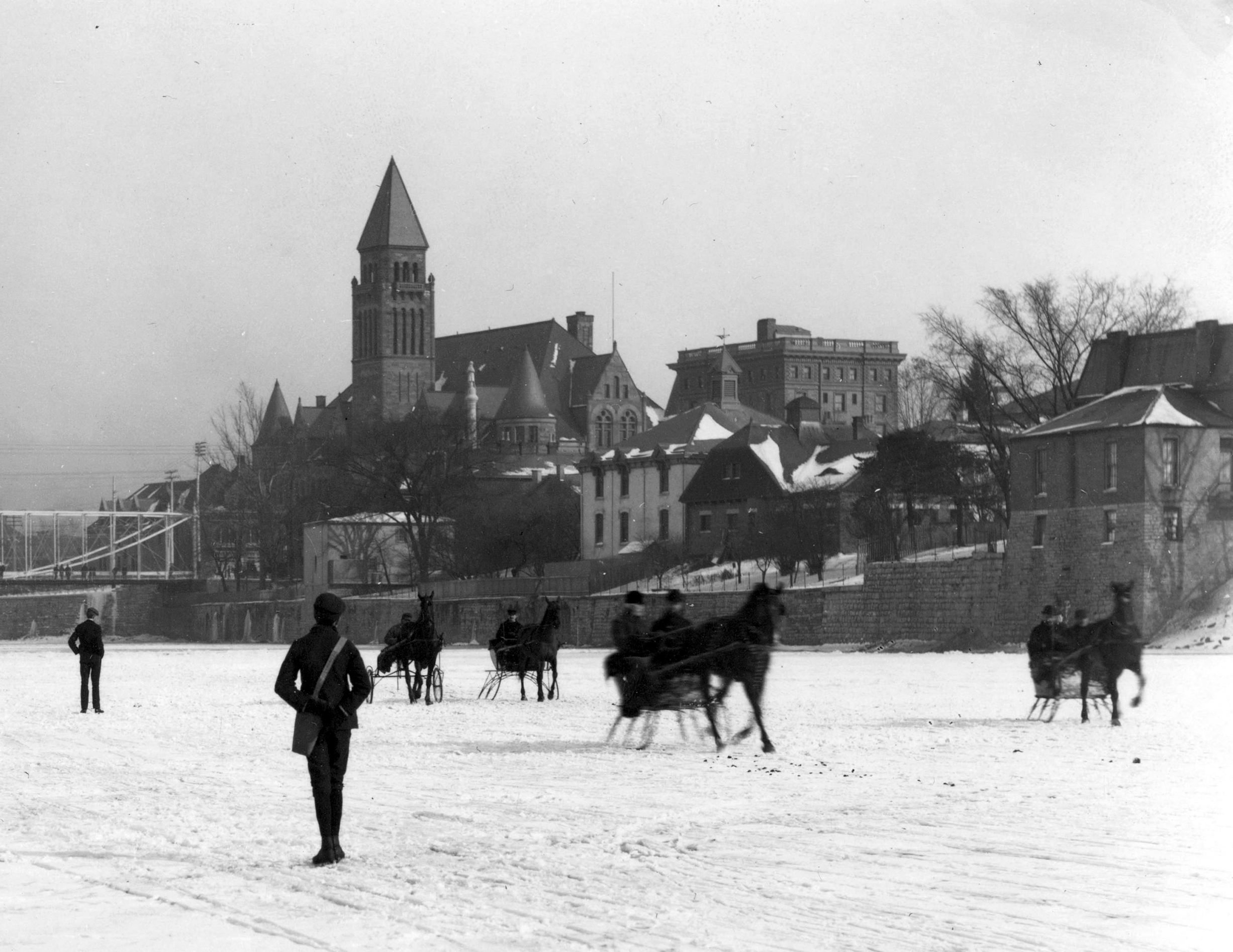 Daytonians ice skating on the Great Miami River. The picture was taken from the river, looking east toward the Main Street Bridge, which can be seen in the background. The old steel bridge in the picture was replaced in 1902 with a steel concrete-bridge. DAYTON METRO LIBRARY