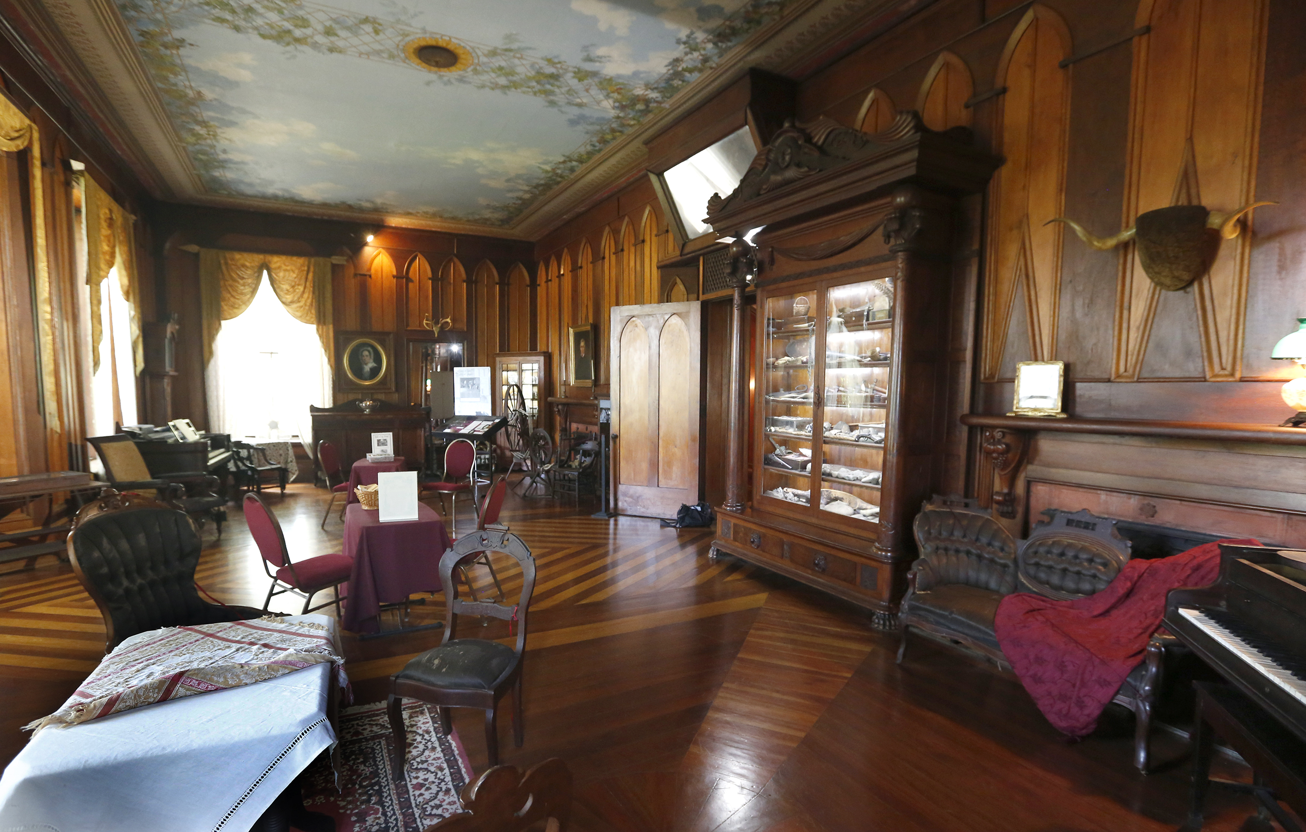 Margaret Piatt calls the drawing room at Mac-A-Cheek âthe best room with the best things in it.â It was the original portion of the home that opened as a museum in 1912. A massive cabinet filled with natural history treasures collected by William McCoy Piatt is at right. LISA POWELL / STAFF
