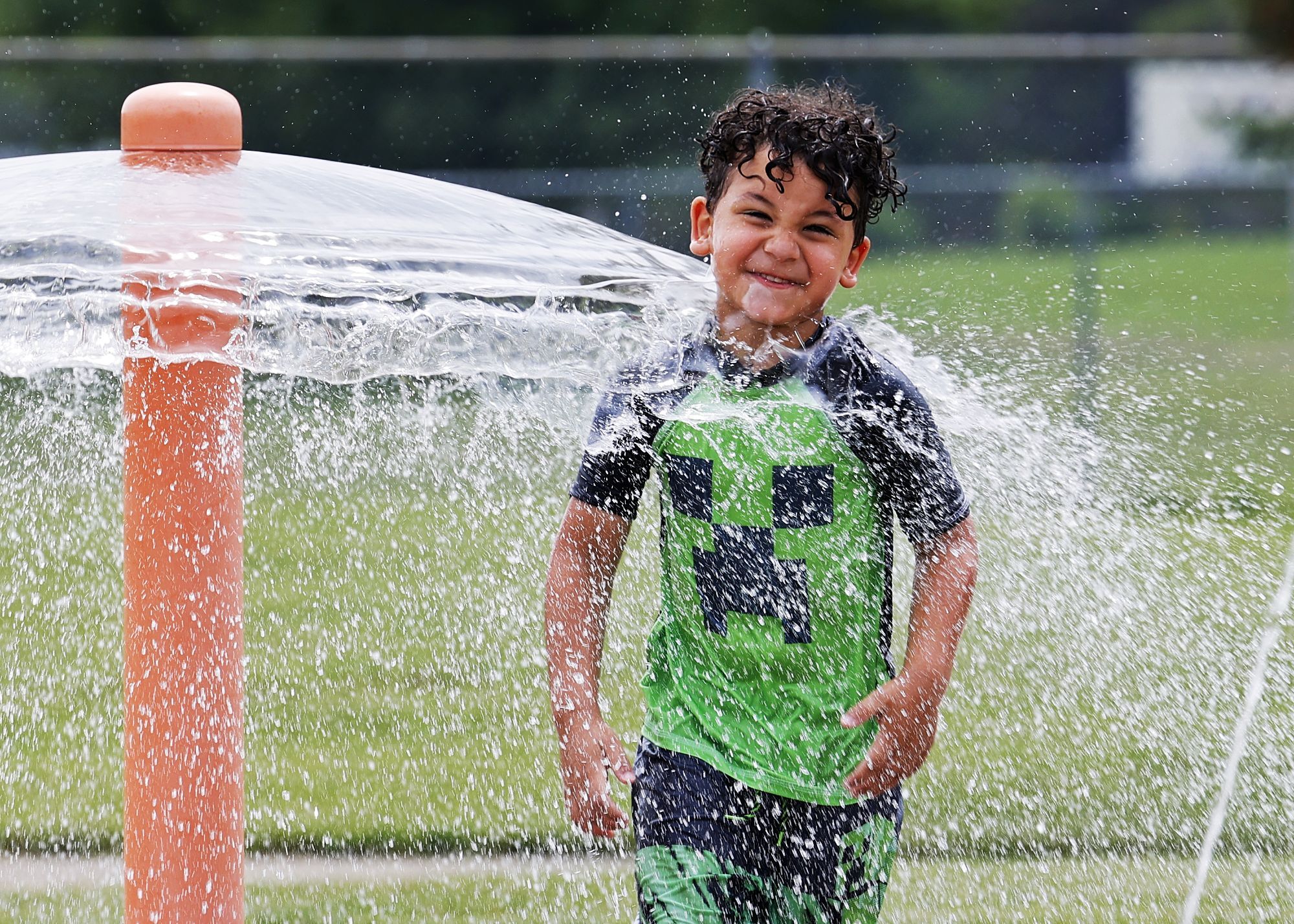 Ian Bailey, 4, cools off in the water at the Booker T. Washington Community Center irrigation area Monday, June 13, 2022, in Hamilton.  NICK GRAHAM/STAFF