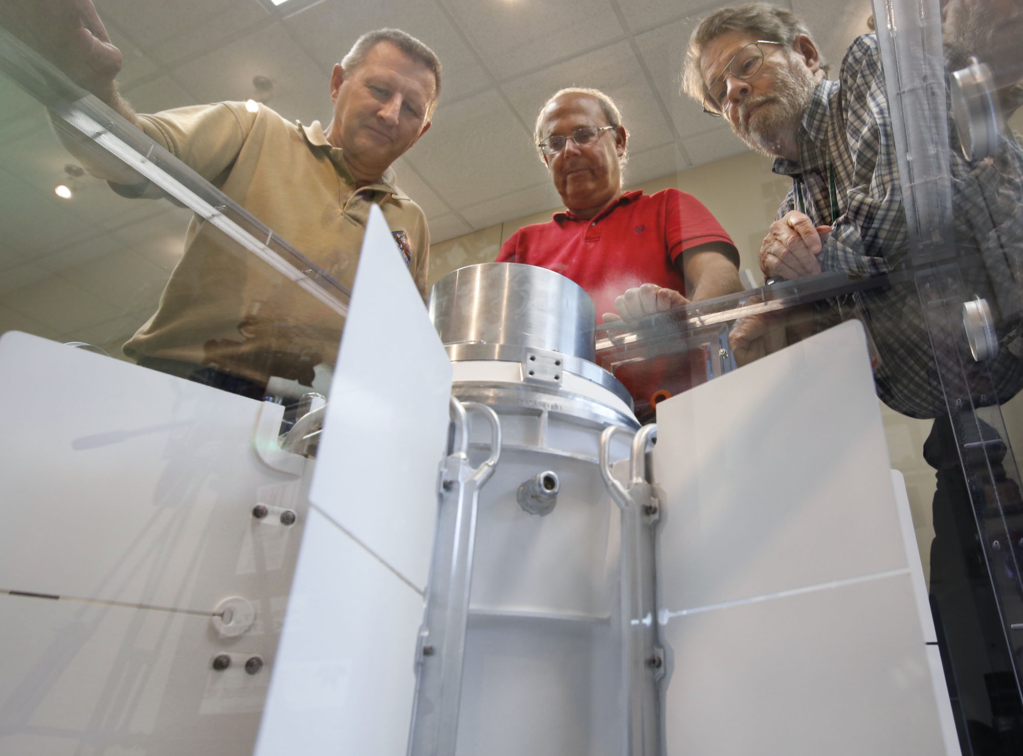 University of Dayton Research Institute scientists and engineers Chadwick Barklay, left, Daniel Kramer and Richard Harris observe a Multi-Mission Radioisotope Thermoelectric Generator that converts the heat from the natural decay of a plutonium-238 dioxide to electricity through solid-state thermoelectric couples. Their laboratory is testing two of the MMRTG units that are cousins of the of New Horizons Pluto mission power unit designed in Dayton. TY GREENLEES / STAFF