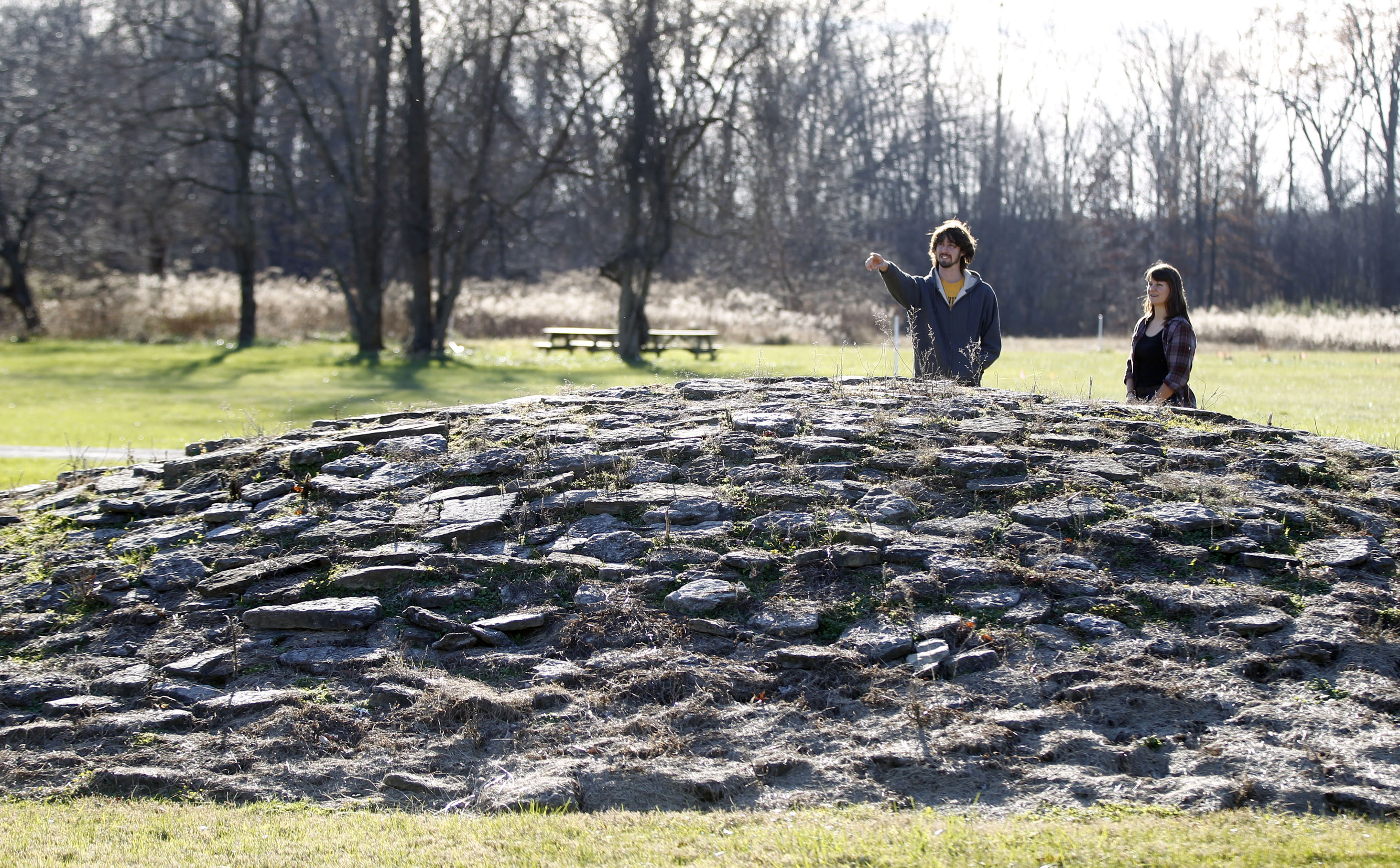Visitors Matt Berger, left, and Kristen Wickert observe a mound at Fort Ancient that is astronomically aligned with the Winter Solstice. Fort Ancient Earthworks outside Lebanon are one stop on the Ancient Ohio Trail, a system of Native American heritage sites a retired UC professor is turning into a global tourist attraction.John Hancock, a retired architecture professor at UC, is also helping put together the application for Fort Ancient, managed by the Dayton Society of Natural History, and other Ohio sites to be designated as a World Heritage Site. But the Ancient Ohio Trail is a separate initiative designed to draw tourists to Ohio. TY GREENLEES / STAFF