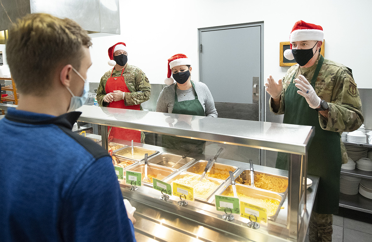 Col. Patrick Miller (center left), 88th Air Base Wing and installation commander; his wife, Beth; and Chief Master Sgt. Jason Shaffer, 88 ABW command chief; serve Christmas dinner to Airman 1st Class Nathaniel Tillman on Dec. 16 in Pitsenbarger Dining Facility at Wright-Patterson Air Force Base. Miller and Shaffer faced a series of challenges and triumphs the past two years as they maintained base operations during COVID-19 restrictions. U.S. AIR FORCE PHOTO/R.J. ORIEZ
