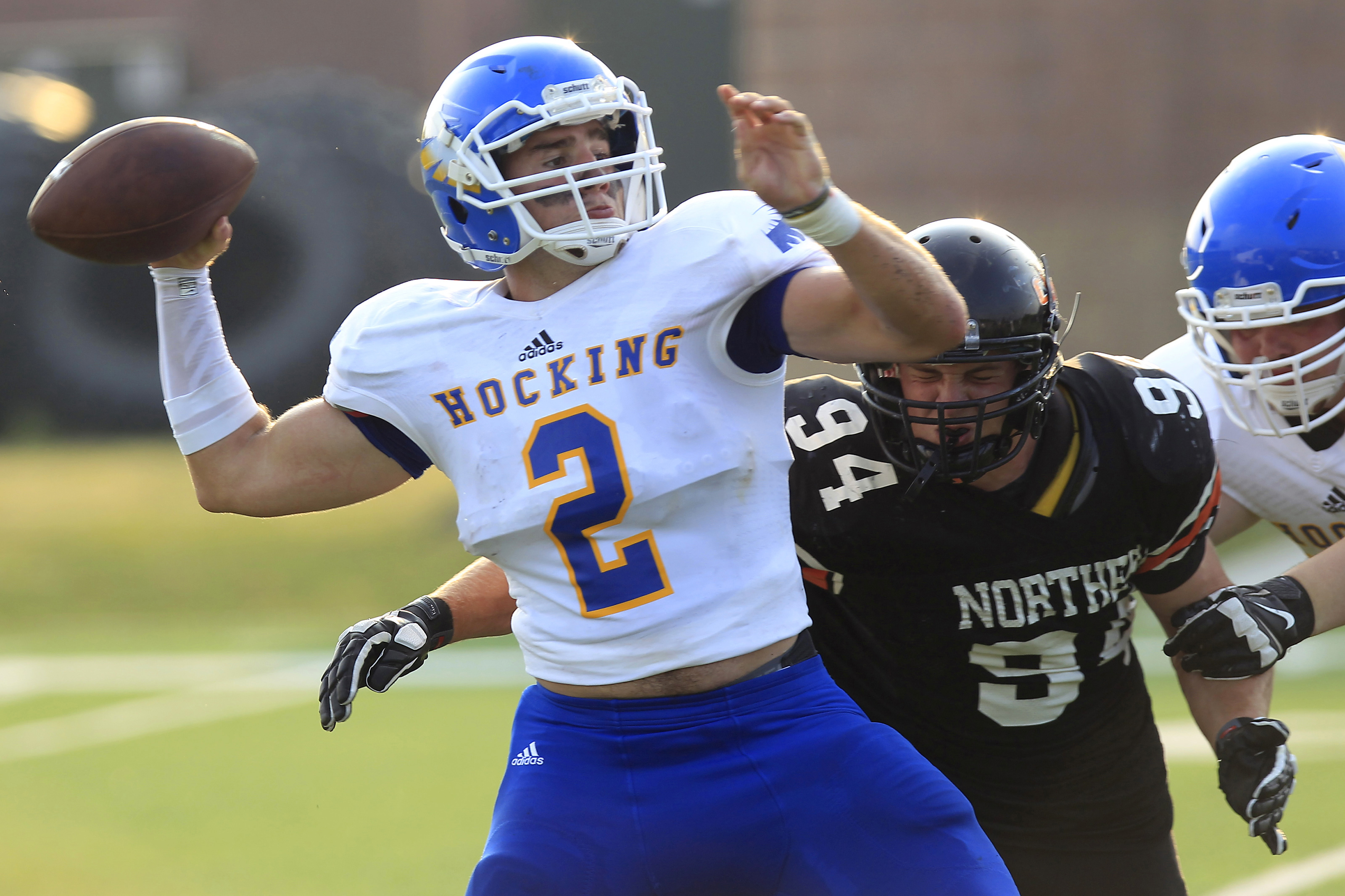 Hocking College’s Trent Mays (2) throws the ball before being hit by Ohio Northern’s Garrett Norman (94) during a football game, Monday, Aug. 31, 2015, in Ada, Ohio. With falling enrollment and a financial crisis that led to three dozen layoffs earlier this year, Hocking College officials came up with an unexpected strategy for raising the profile and attracting more students: they started a football team. (AP Photo/J.D. Pooley)