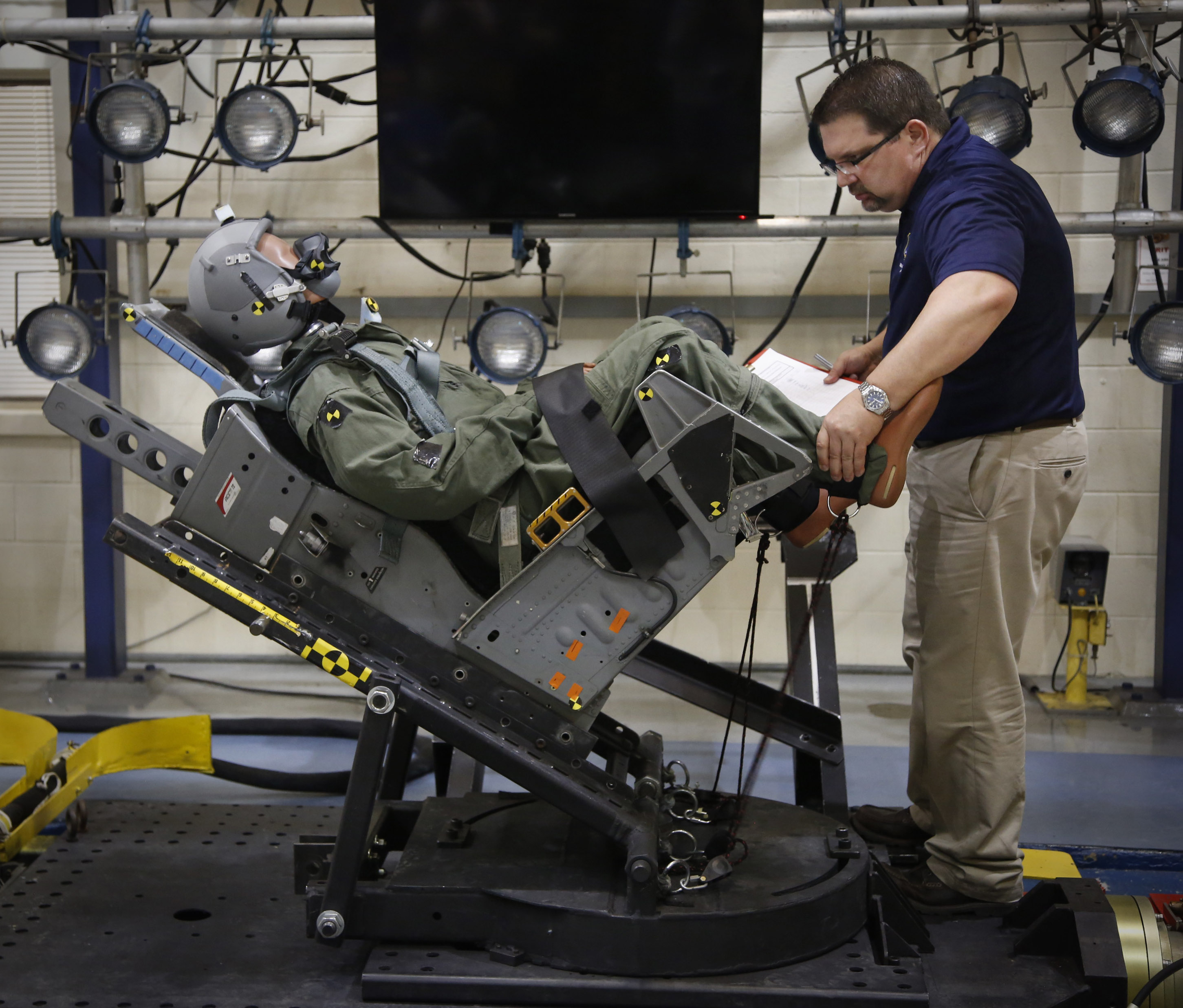 A mannequin is strapped into an ejection seat and secured by Chris Perry at the Aircrew Biodynamics and Protection Facility on Wright-Patterson Air Force Base where it was shot down a rail to measure the gravitational force, or G-force it experiences during a simulated ejection from a jet. The lab has been busy testing a larger envelope of pilot weights, the F-35 Joint Strike Fighter and its new ejection seat. TY GREENLEES / STAFF