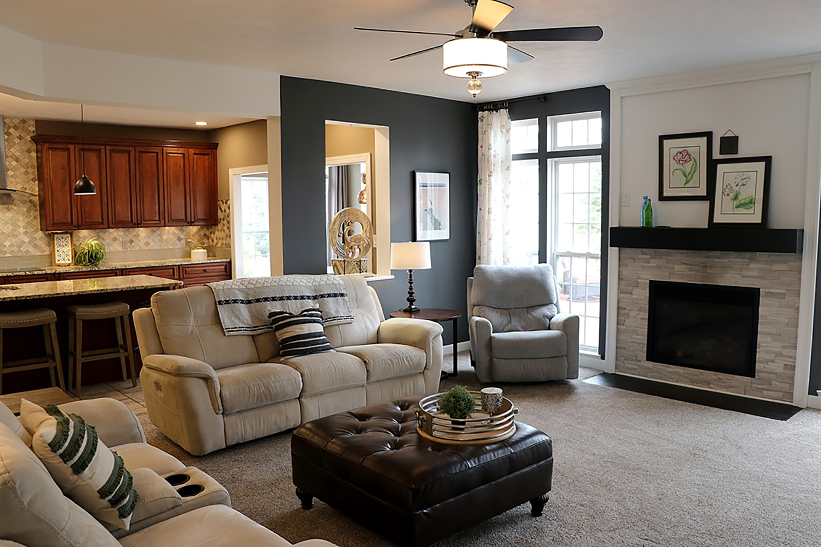 In the great room, a gas fireplace has a stone surround and a wood-beam mantel and a wood hearth. Tall windows with transoms above flank the fireplace and a cutout looks into the breakfast room. CONTRIBUTED PHOTO BY KATHY TYLER