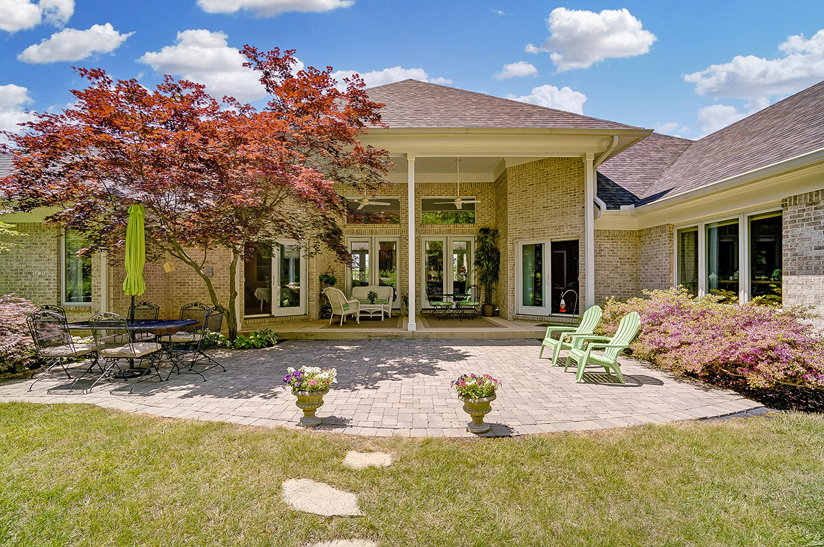 The rear of the home features a covered rear concrete patio with double ceiling fans. The patio steps down to a paver patio extension, surrounded by landscaping and leading the back lawn. CONTRIBUTED PHOTO