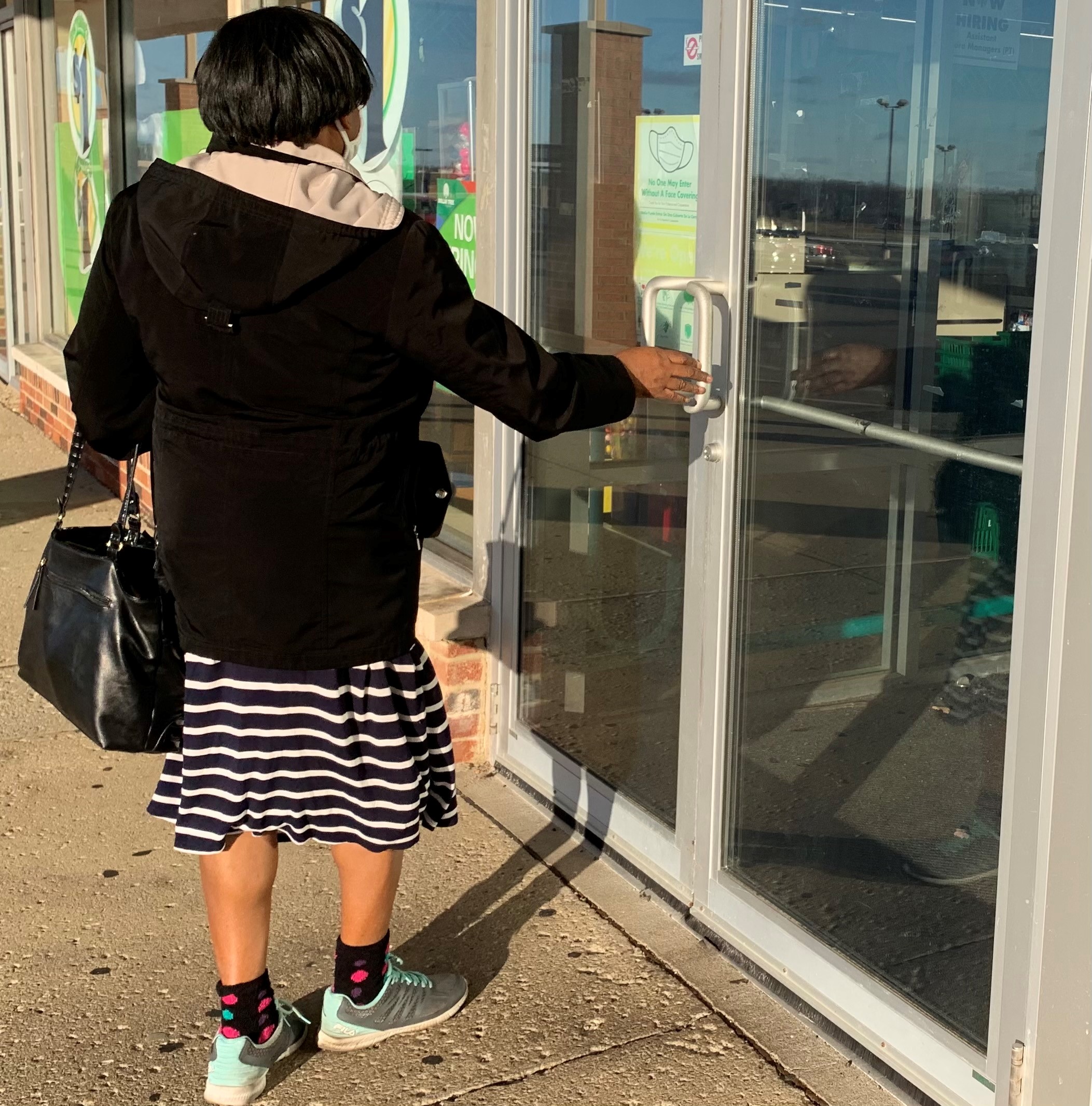 A shopper enters the Dollar Tree in Trotwood wearing a mask.