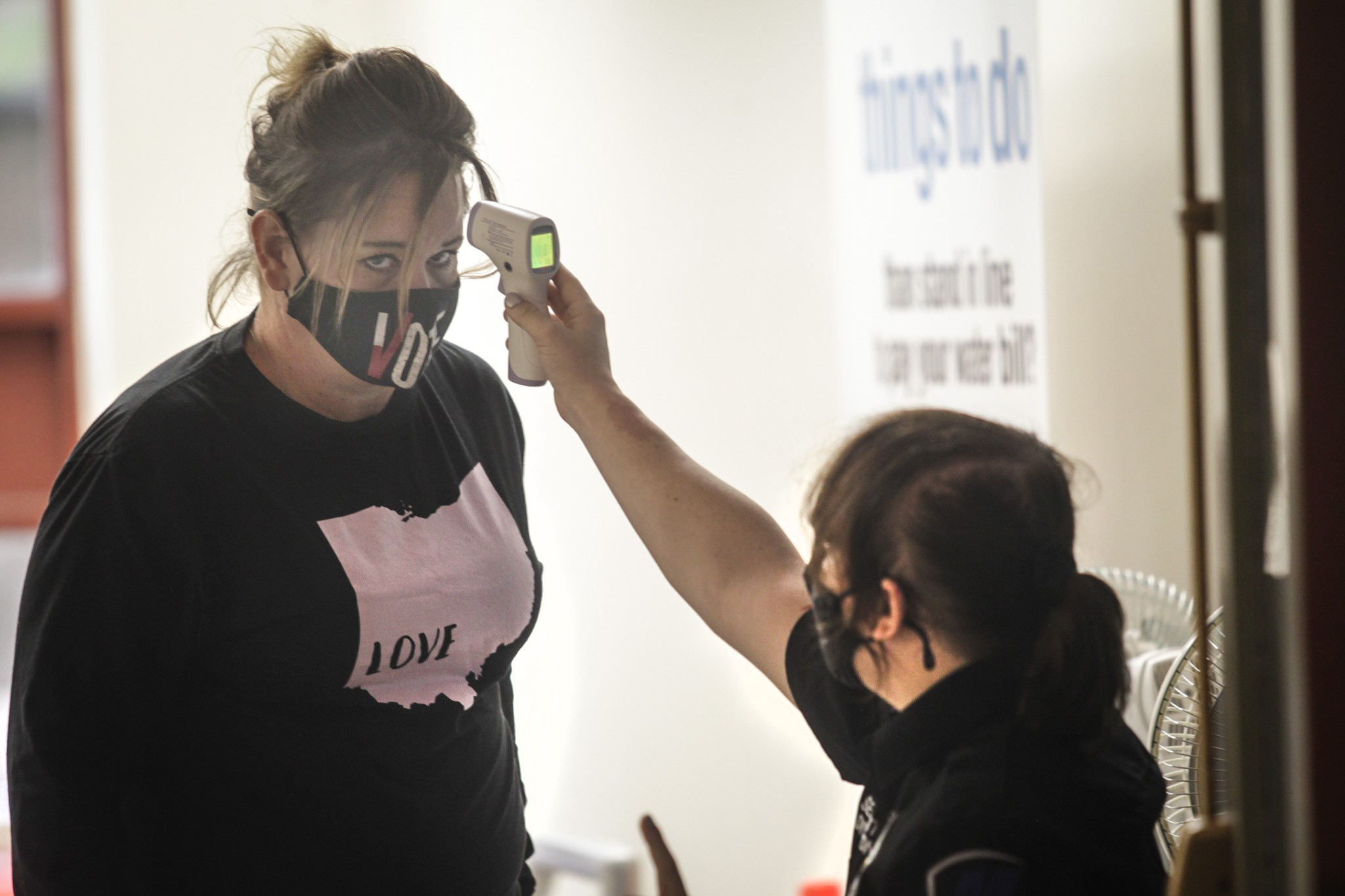 Security guard at City Hall, Lilith York checks the temperature of Lisa Antrican as she enters the building on Ludlow St. to pay her water bill Thursday October 1, 2020.