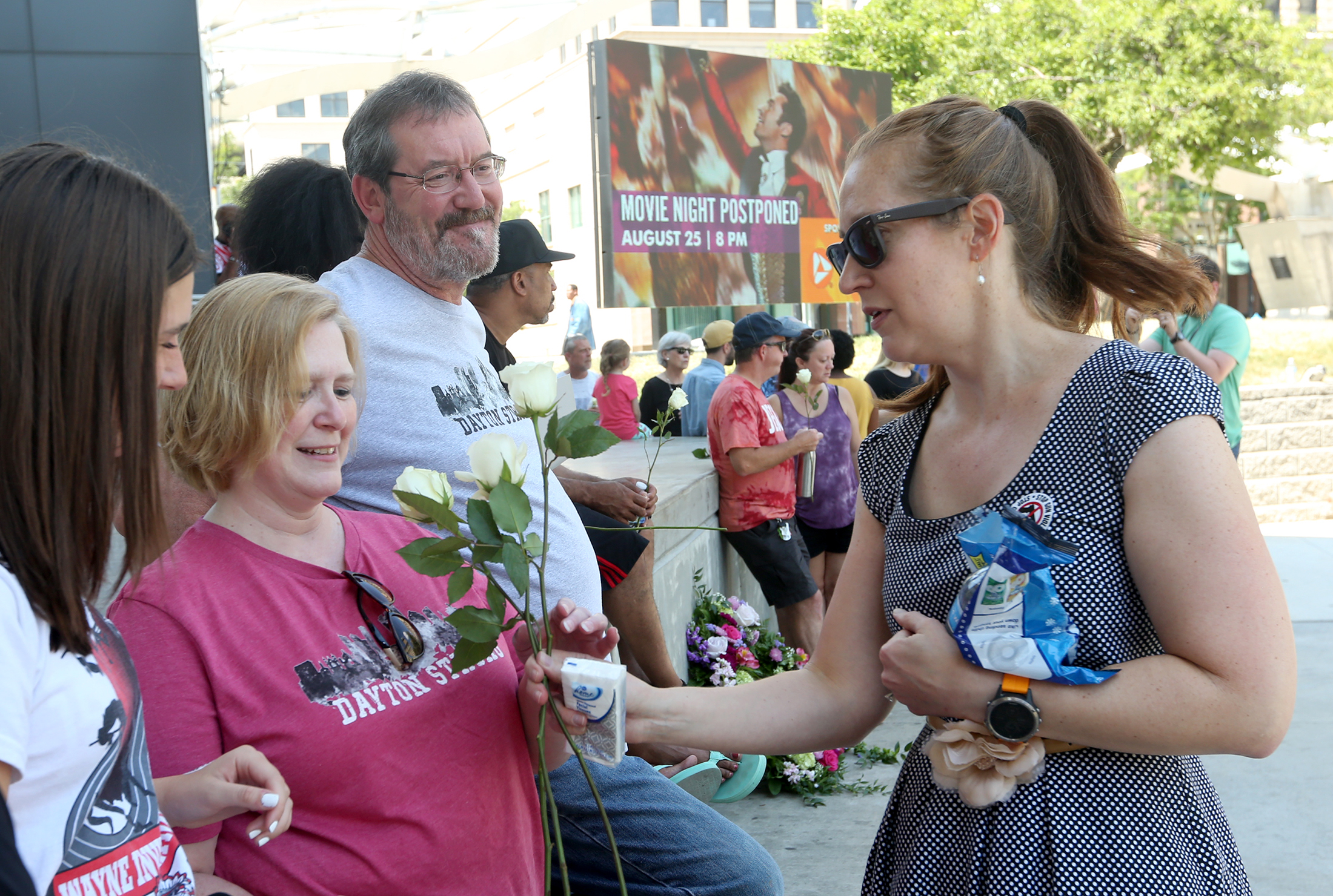 Lindsey Posey and her husband Terry handed out white roses, tissues and mints to people gathered for a vigil at the Levitt Pavilion Sunday. LISA POWELL / STAFF
