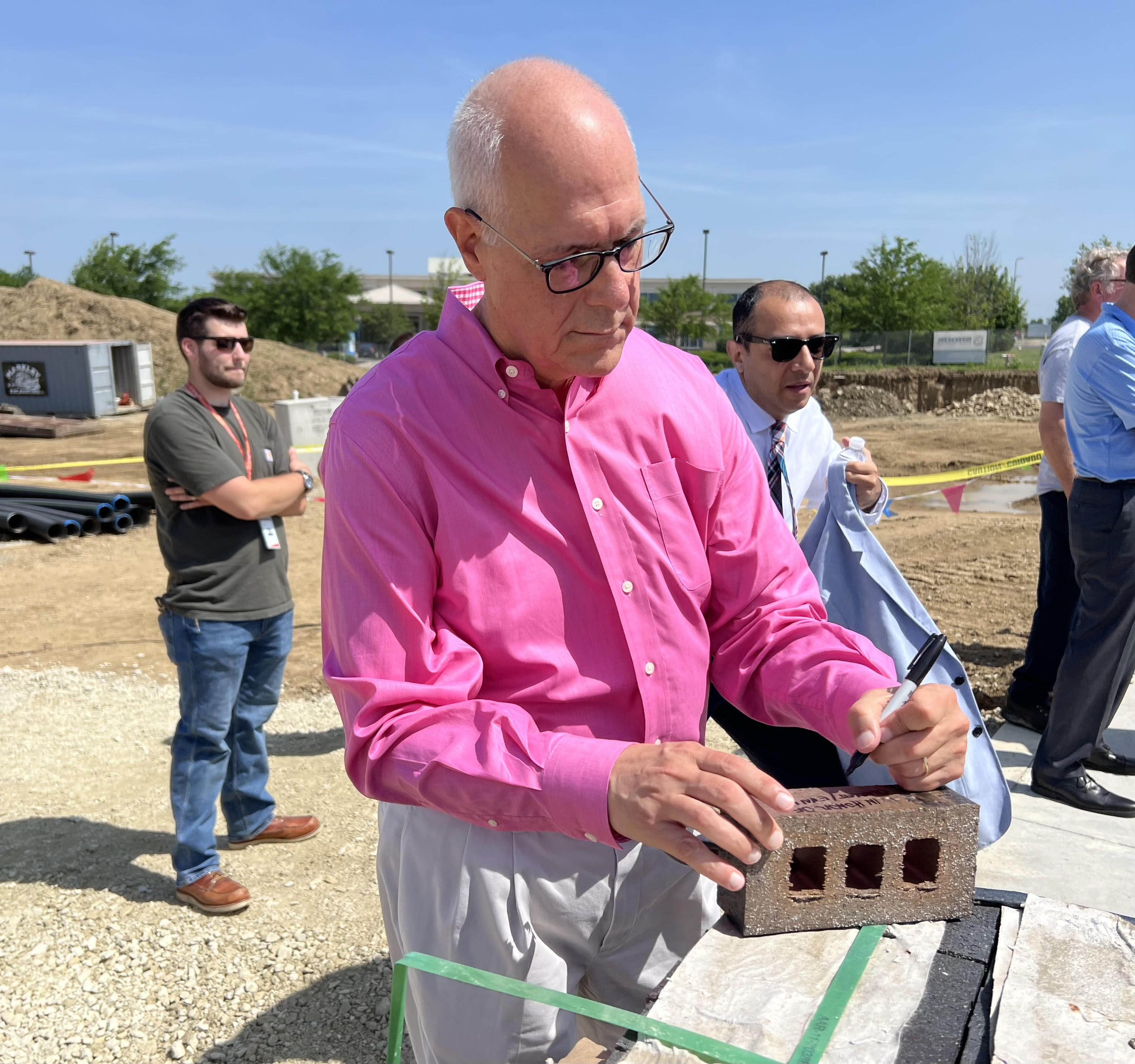 Bear Monita, partner for LWC Inc. architectural firm, signs a brick during Tuesday's commemorative groundbreaking event for the Dayton Metro Library's new Huber Heights branch. The signed bricks will be used in the construction of the facility. LWC is the project architect. AIMEE HANCOCK/STAFF