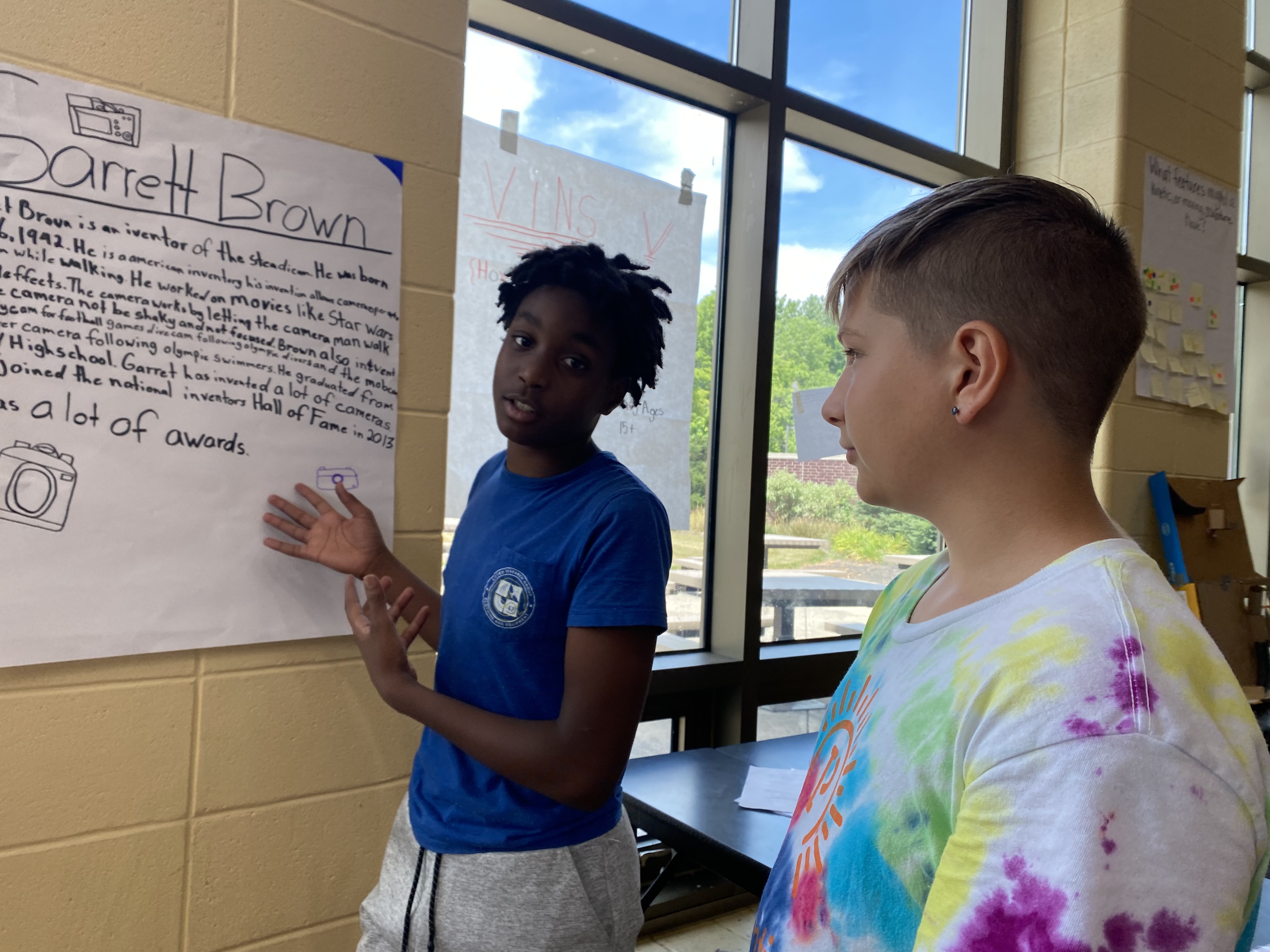 Lamar Lynch, an eighth grader in Huber Heights schools, presents a poster he made during STEM camp at Weisenborn Middle School while Blake Beeching, another eighth grader on Lynch's team who also worked on the project, looks on. Eileen McClory/ staff
