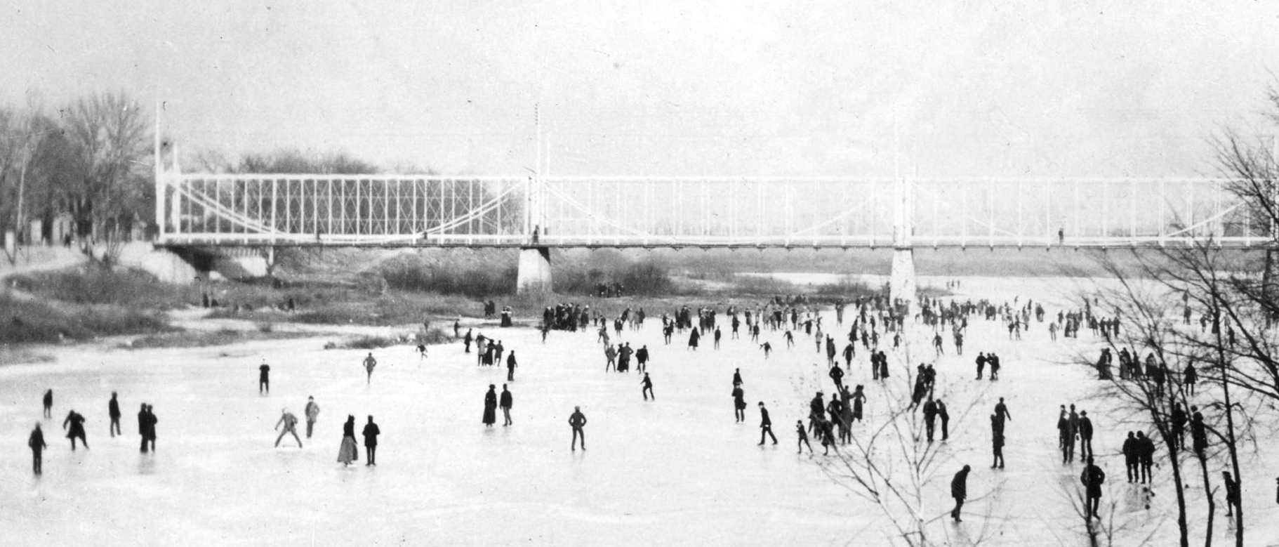 Ice skating on the Miami River on January 2, 1901. On this day the ice was twelve inches thick. Picture taken from the bank of the Miami River looking east toward the Main Street Bridge. The old steel bridge was replaced in 1902 by a steel and concrete bridge. DAYTON METRO LIBRARY