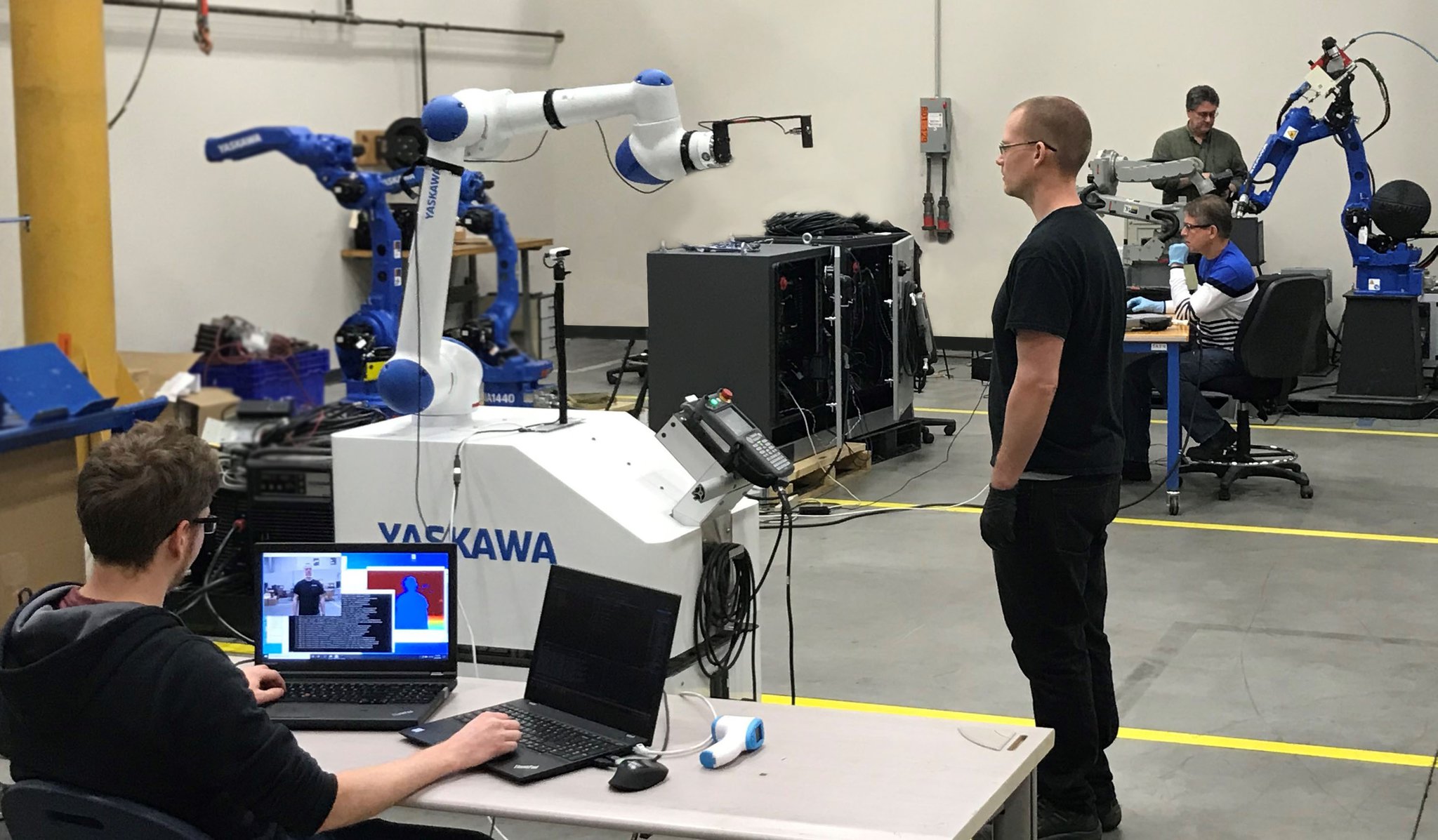 Motoman production employees continued working through the pandemic but office workers were sent home to work. In this photo from May 2020 employees test a collaborative robot that was able to take employees temperatures when they arrived to work at the Miamisburg firm. From left are Matthew Hartshorn, Jayson Noll, John Elliott and Greg Morgan.