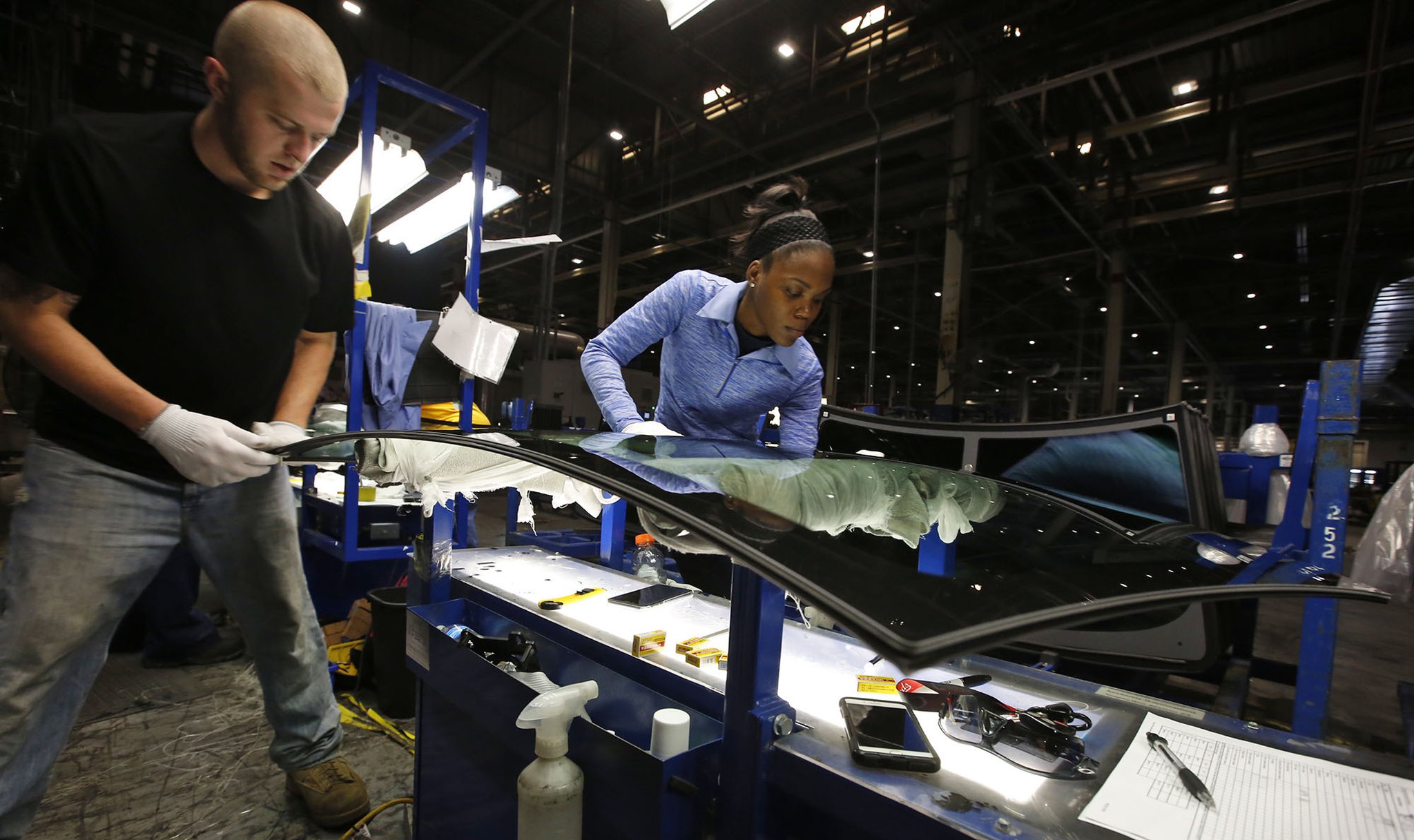 Fuyao Glass America has progressed at a pace that is years ahead of its original schedule and now employs more than 2,000 people. Dustin Sparkman, left, and Deraesha Stewart work as a team to clean and quality check windshields in the Moraine plant.. TY GREENLEES / STAFF