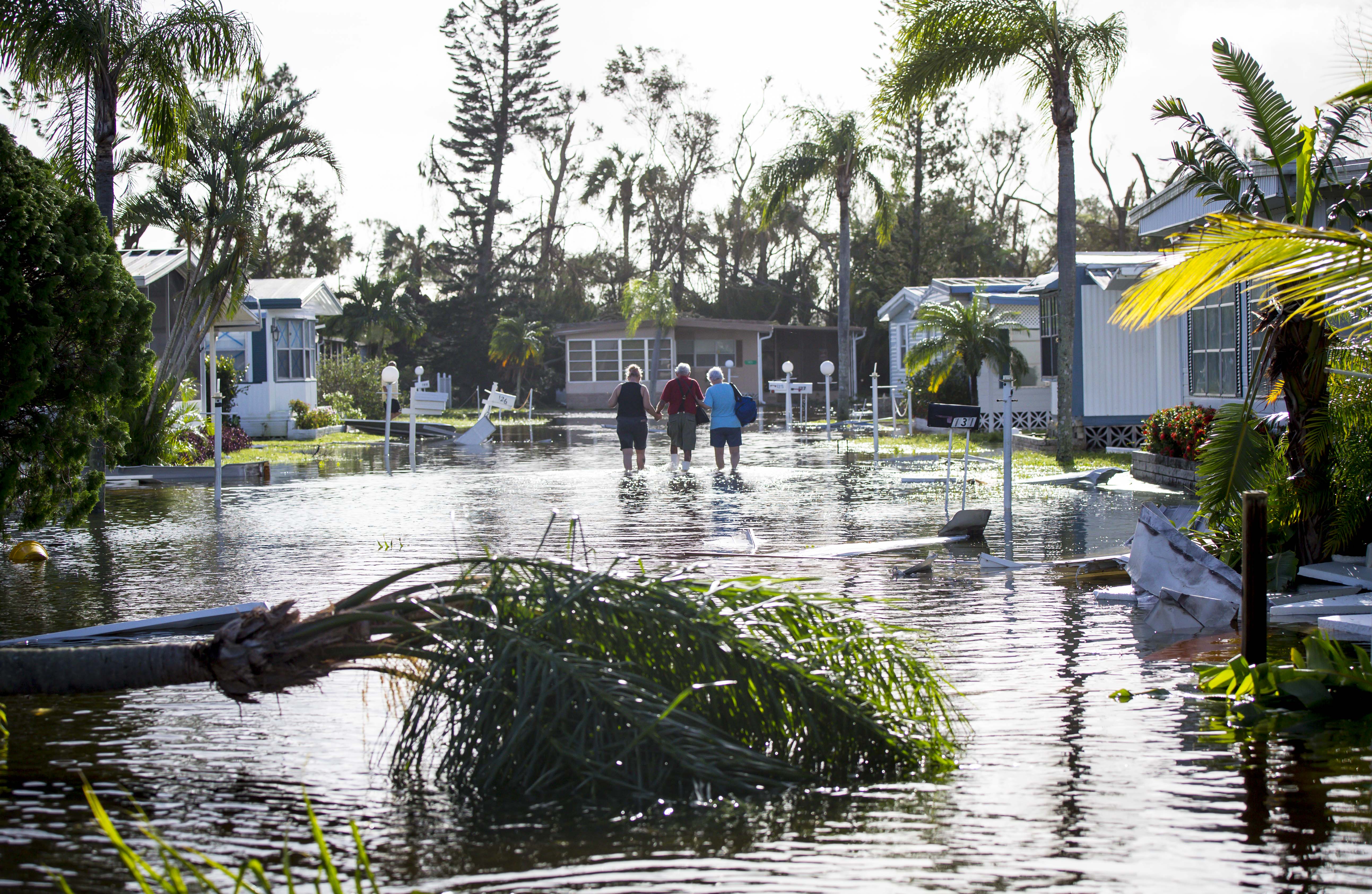 Larry Donnerstaf, center, is helped back to his home at Naples Estates trailer park in East Naples, Fla., on Sept. 11, 2017.