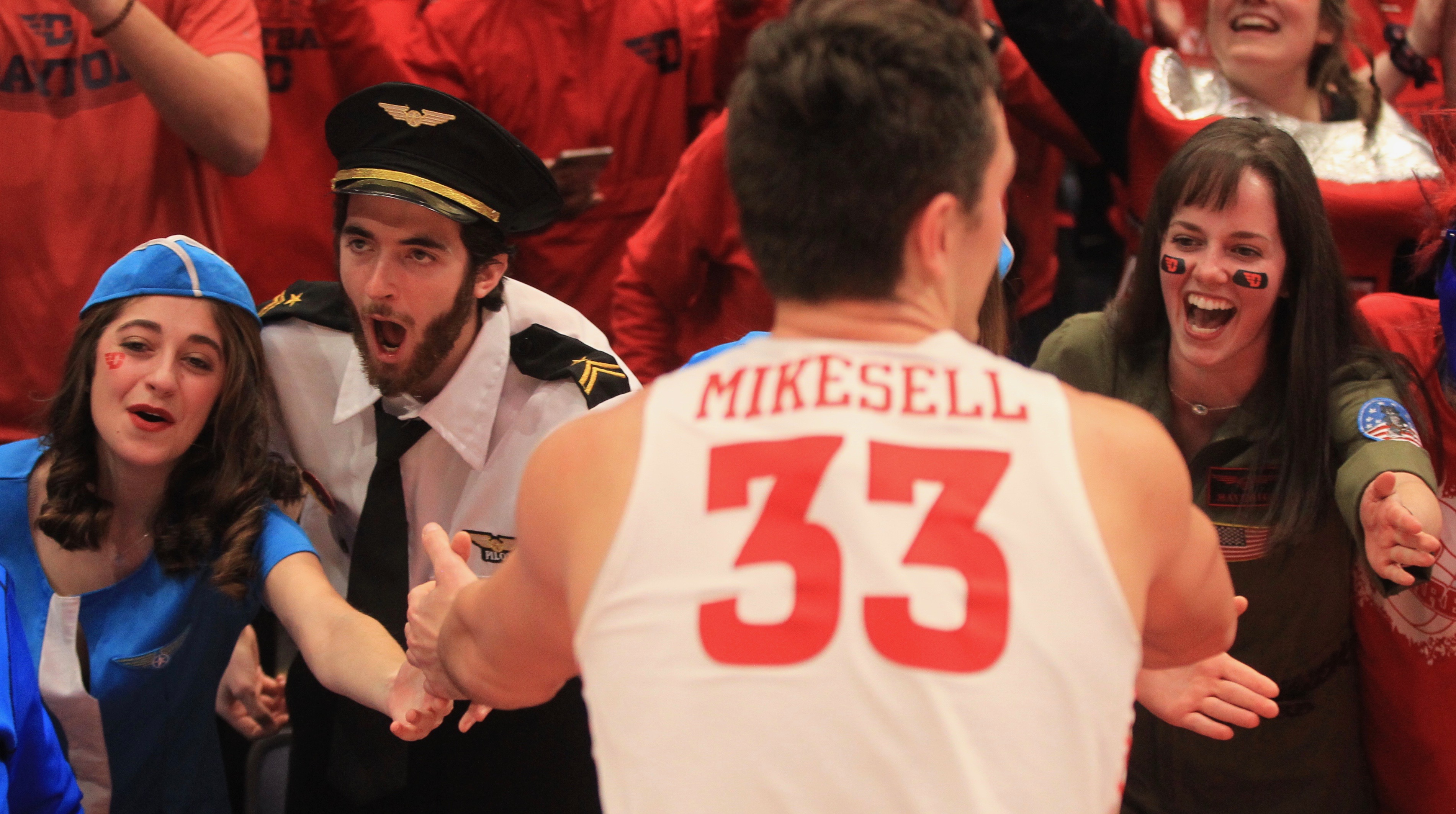 Members of the Red Scare slap hands with Ryan Mikesell after Dayton's victory against Davidson on Feb. 28, 2020, at UD Arena. Pictured (left to rightI are: Annie Montefiori, Michael Oliver and Michelle Smith.