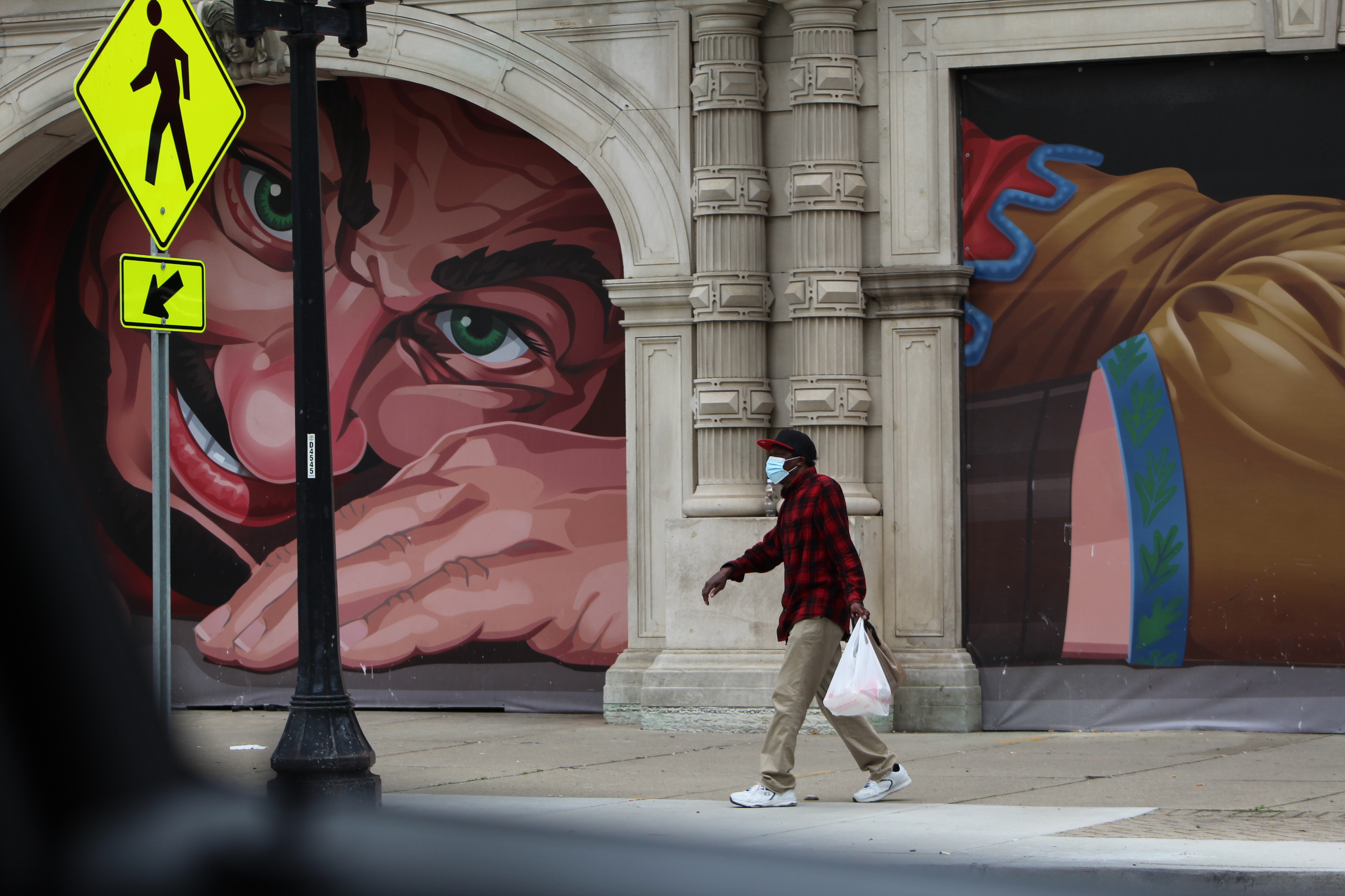 A man walks past the mural on the north end of Dayton Arcade after finishing shopping at Stop-N-Save Foods on West Third Street in downtown Dayton.  Cornelius Frolik / Crew