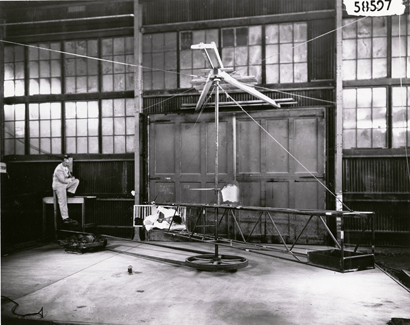 According to the caption on the back of this photograph, this human centrifuge was the first built in the United States. The centrifuge was located in a balloon hangar on the flight line of Wright Field, and was constructed by Capt. Harry Armstrong and Dr. John W. Heim. Human centrifuges were designed to test the resistance of the human body to g-forces, a force commonly felt by pilots. Armstrong, who is pictured sitting on the table to the left, eventually became one of the leading minds in aerospace medicine, and would also serve as Surgeon General of the United States. Interestingly, the centrifuge in this picture has the human subject lying on his or her side. Today’s centrifuges generally have the subject seated in an upright position. DAYTON DAILY NEWS ARCHIVES
