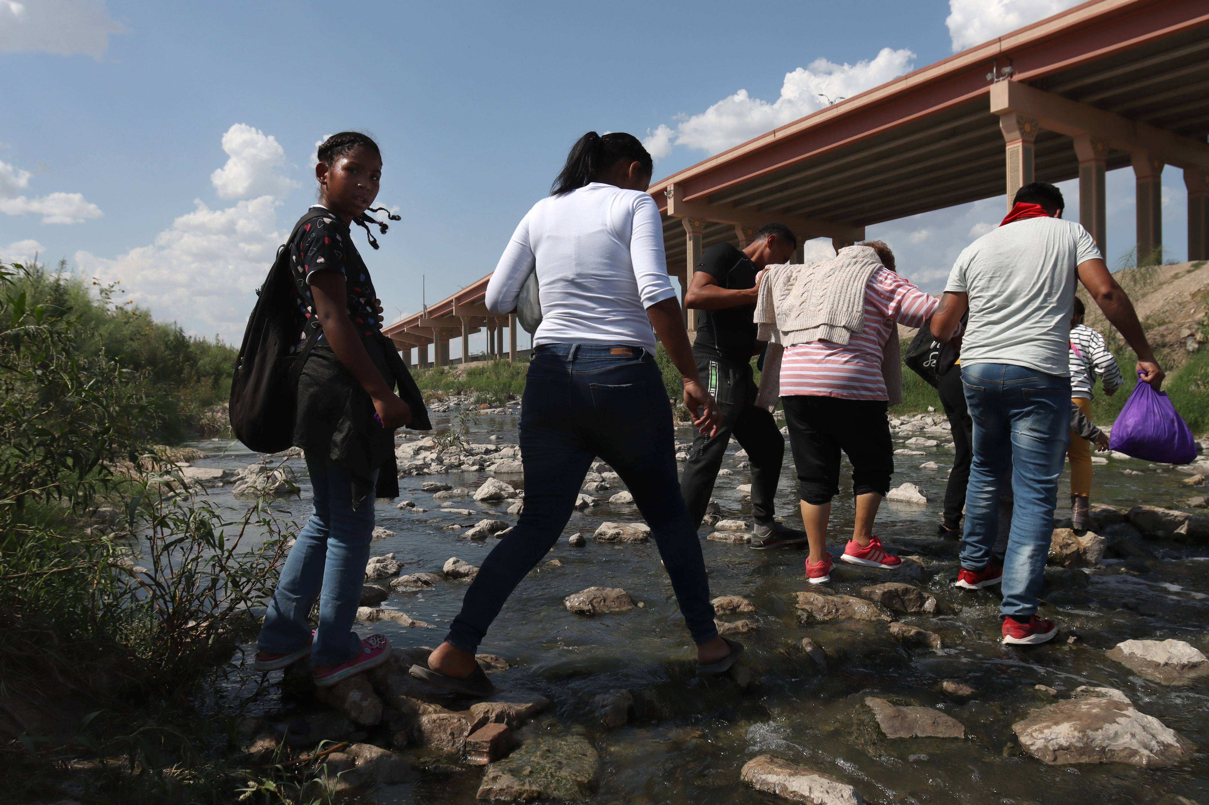 Three migrants who had managed to evade National Guard and cross the Rio  Grande onto U.S. territory wait for Border Patrol along a wall set back  from the geographical border, in El