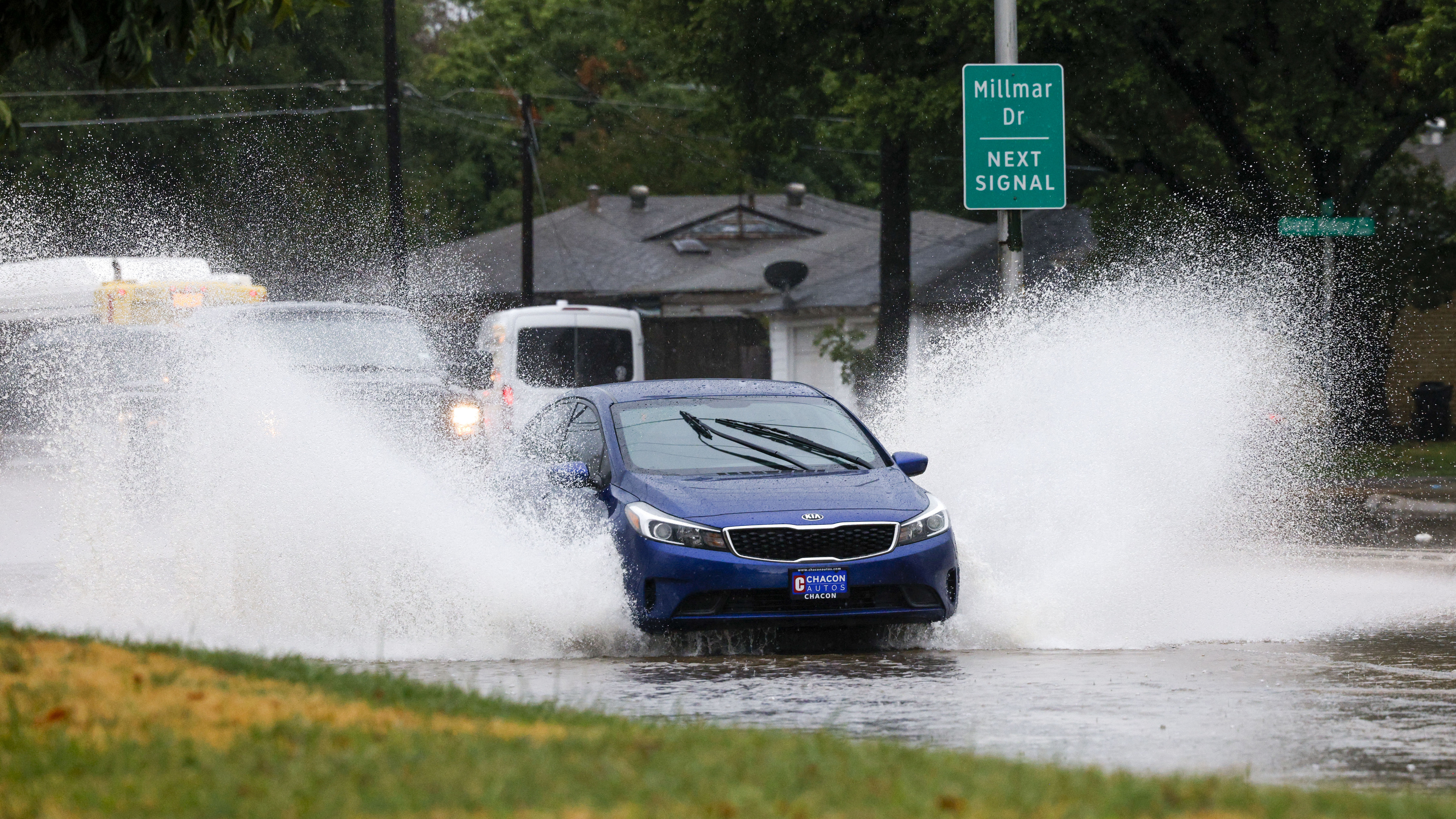 Cars drive through high flood waters along Ferguson Road near Millmar Drive in Dallas,...