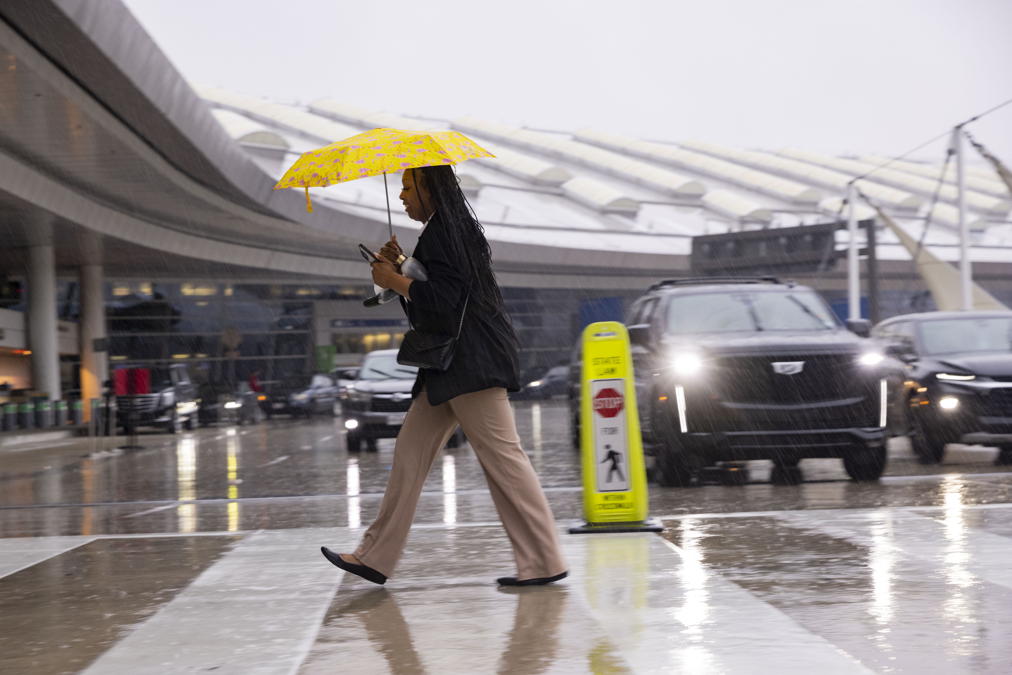 Alexis Alexander crosses the street in the rain to go to work at the Grand Hyatt on Friday,...