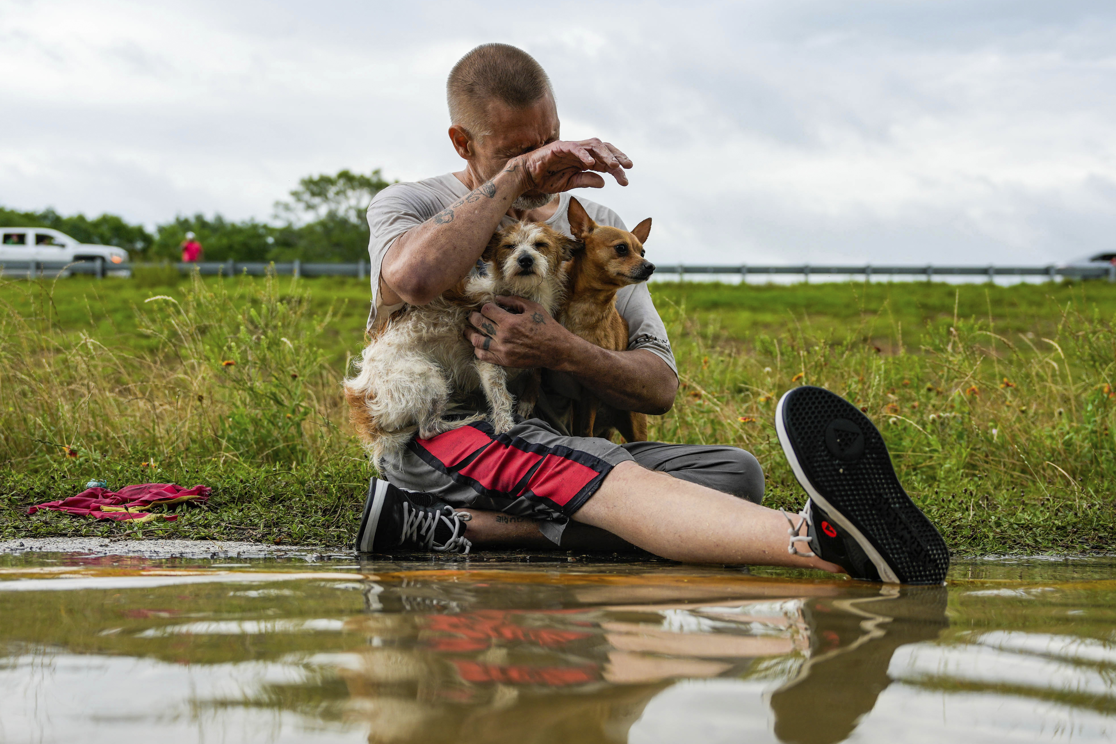 Tim McCanon sits on the road with his dogs after being rescued by the Community Fire...