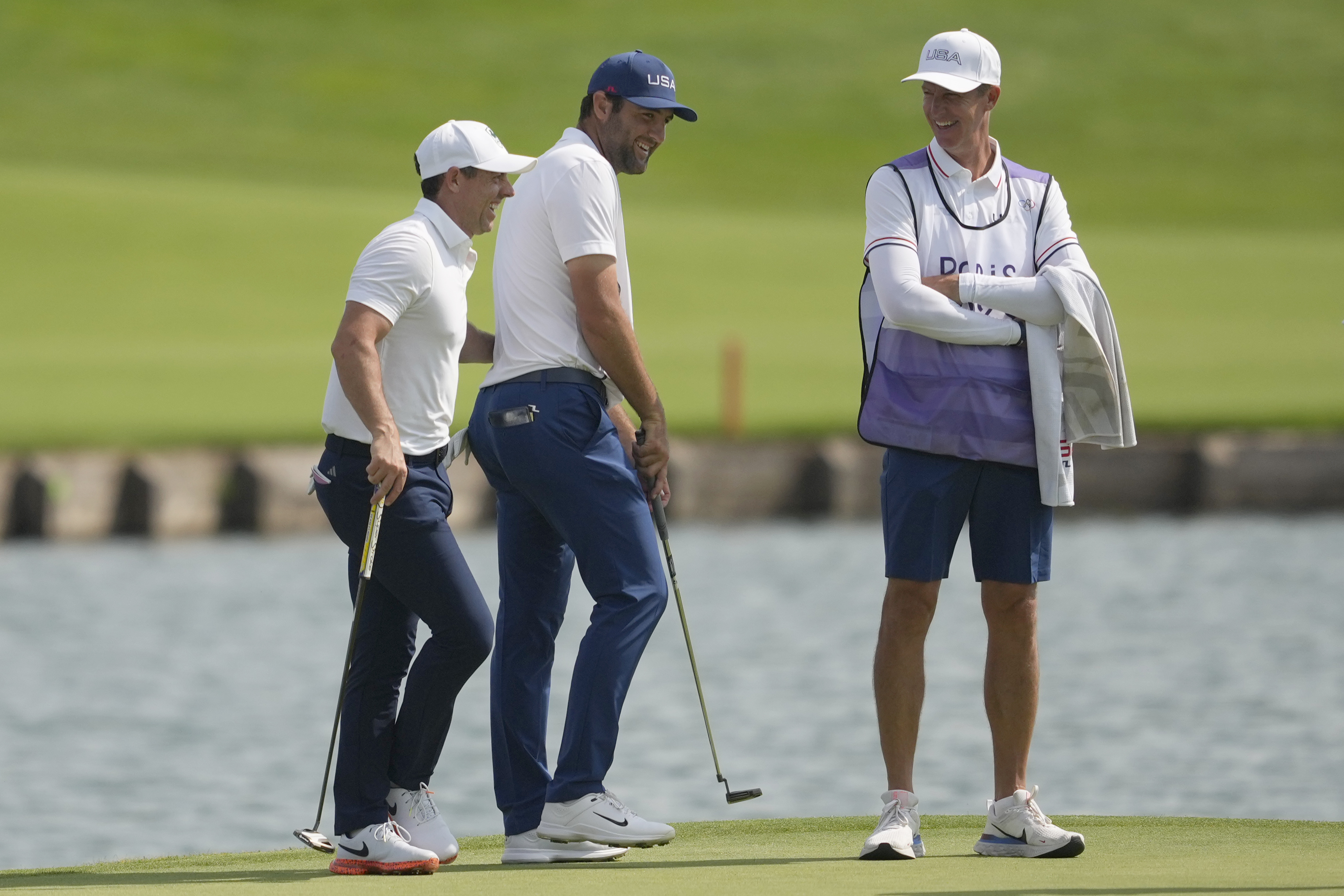 Rory McIlroy, of Ireland, left and Scottie Scheffler, of the United States, centre interact...