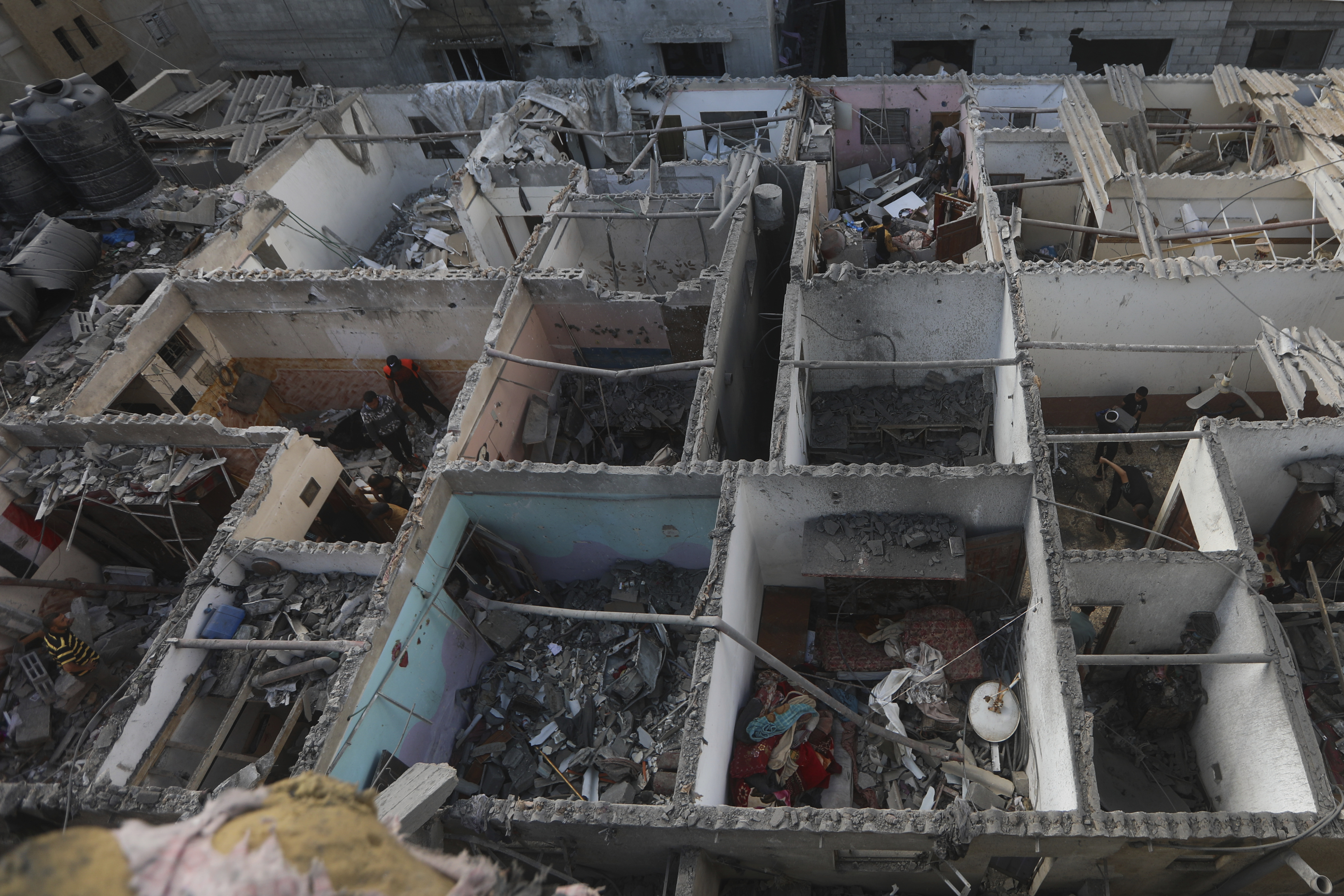 Palestinians look at the destruction after an Israeli strike on residential building in...