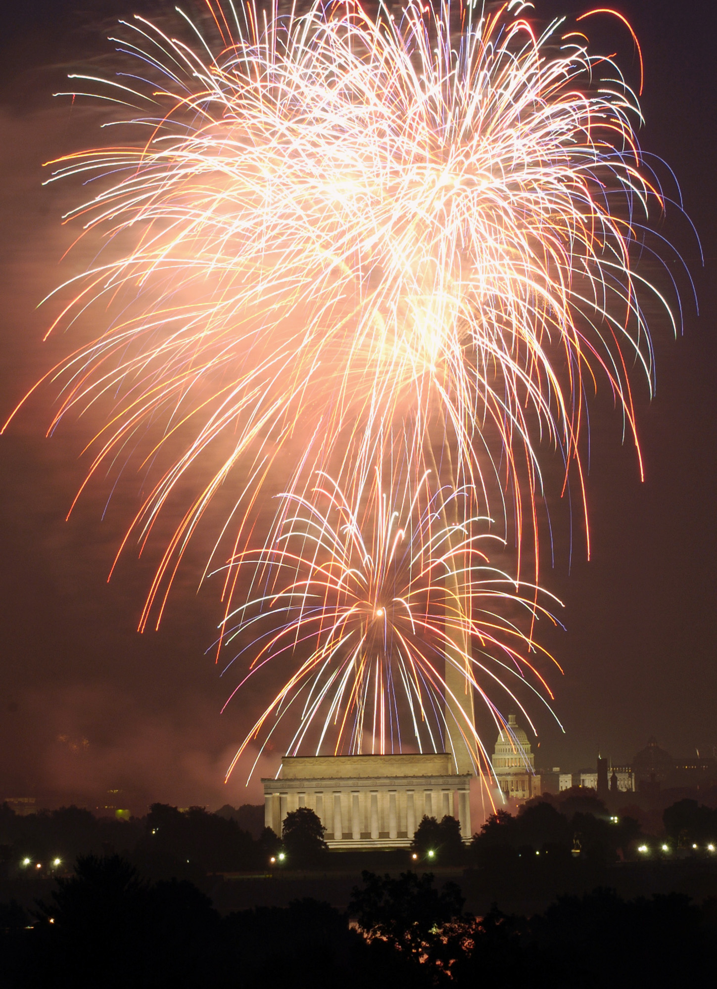 Fourth of July fireworks are seen above, the Lincoln Memorial, the Washington Monument, and...