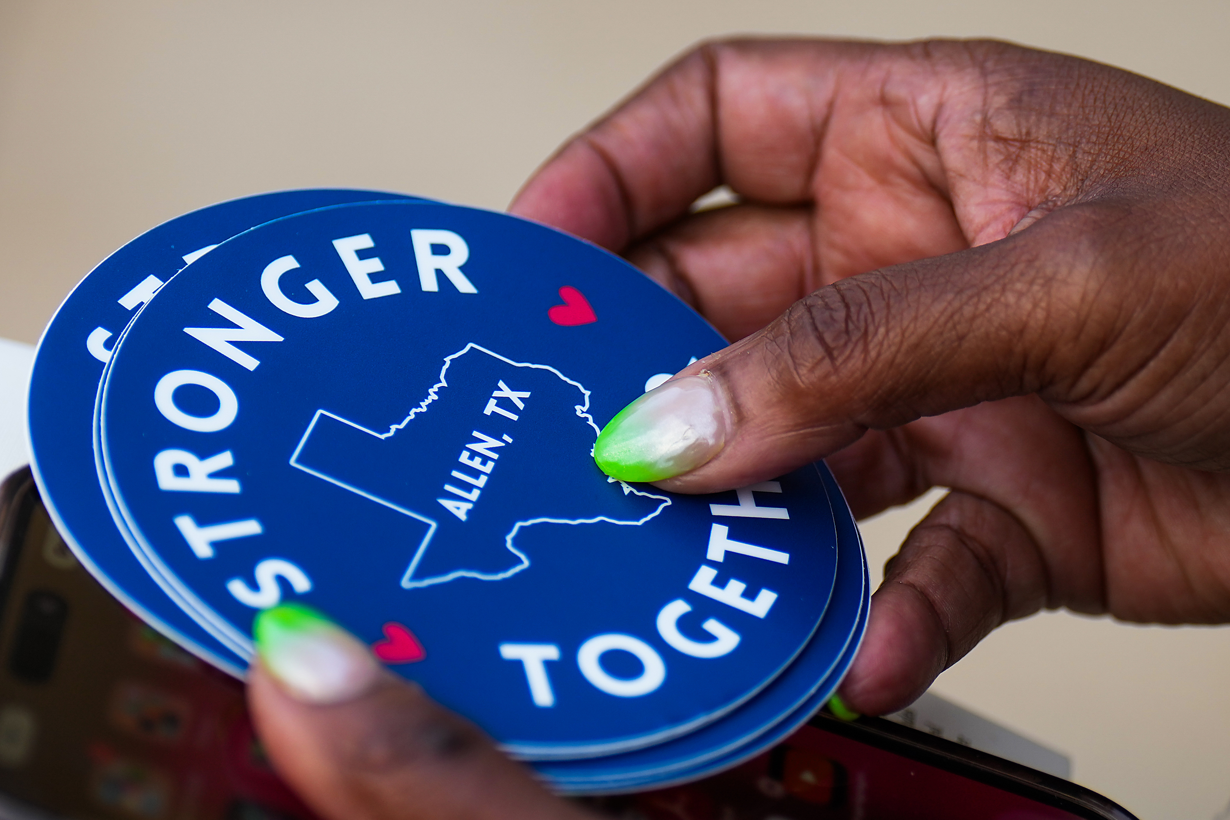 Cheryl Jackson holds stickers reading “Stronger Together” after a remembrance event at...