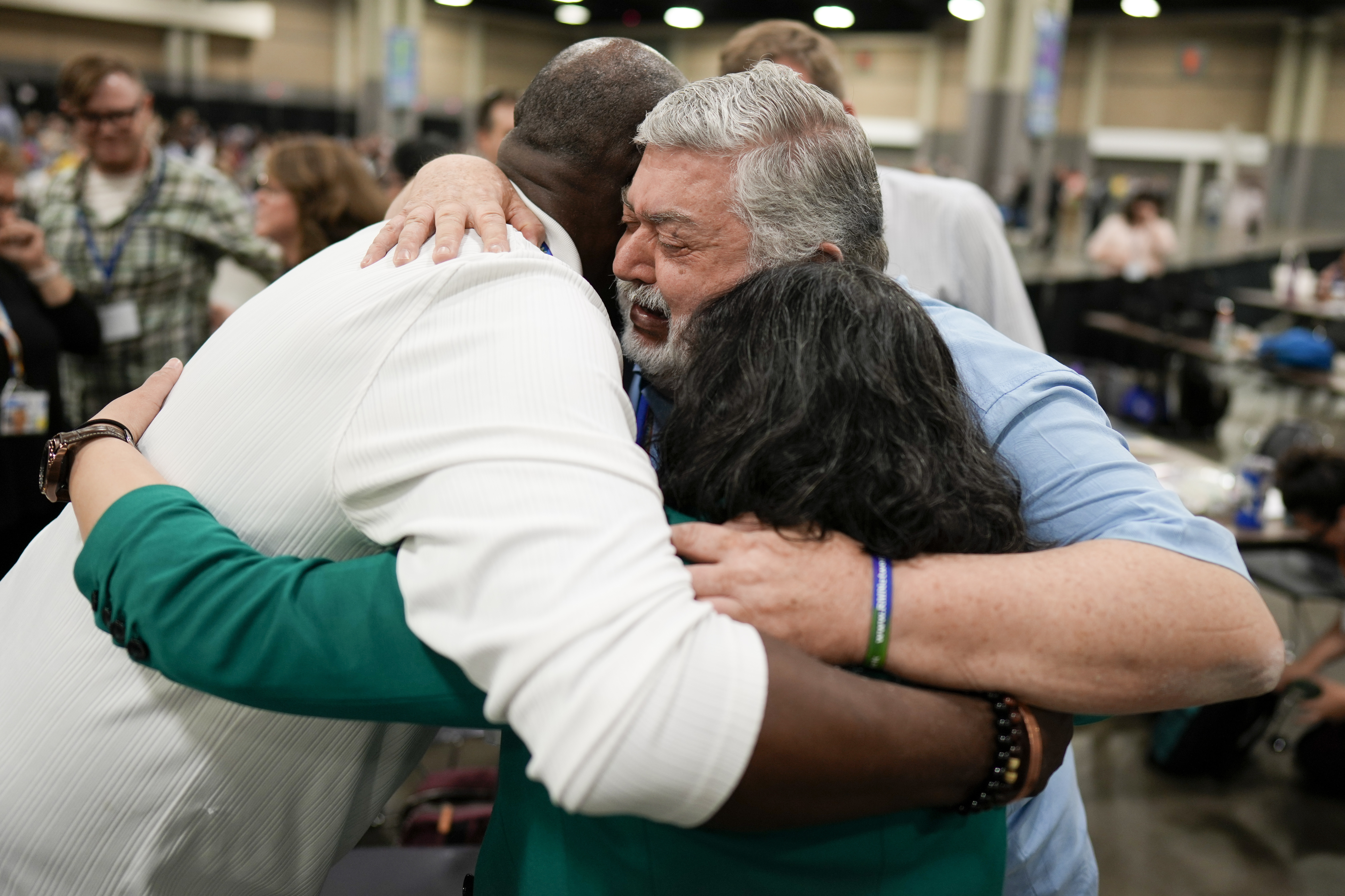 David Meredith (middle) shared a hug after after a vote at the United Methodist Church...