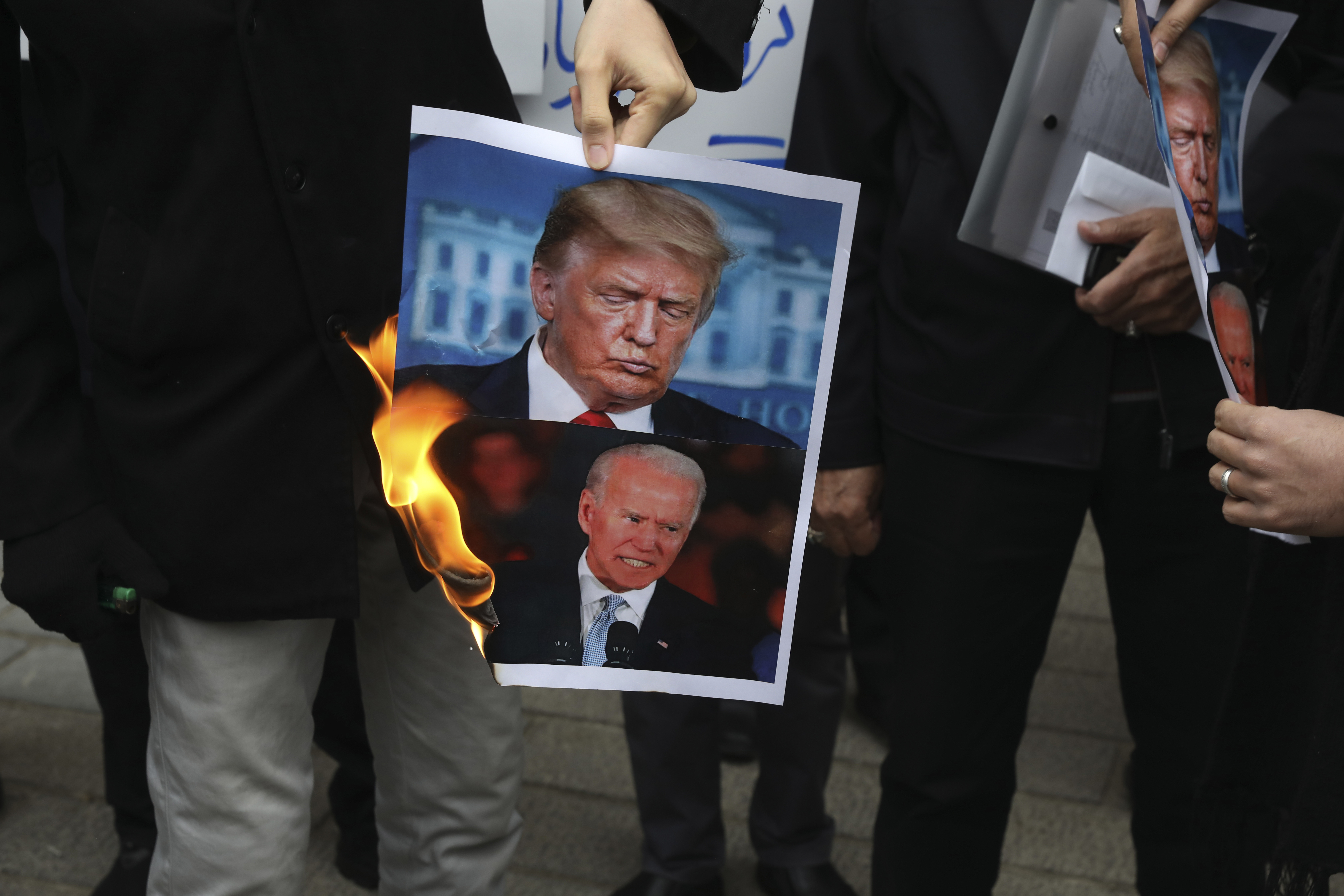 FILE — Protesters burn images of then-U.S. President Donald Trump, top, and...